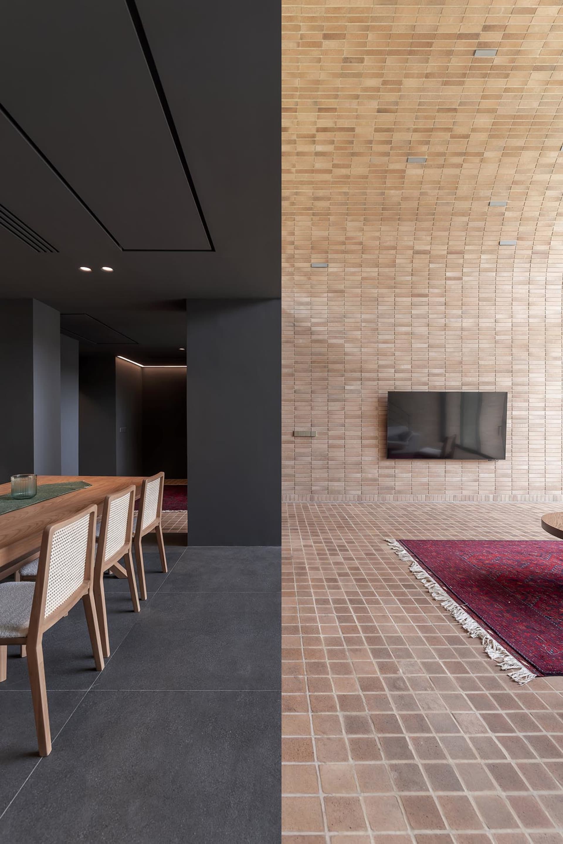 A modern living room featuring brick tiles, a table, chairs, and a television.