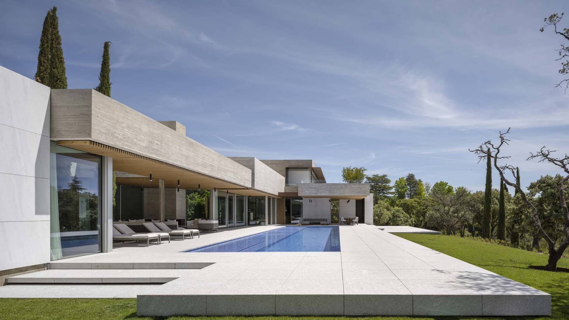 Modern house exterior with concrete structure and garden in the background.