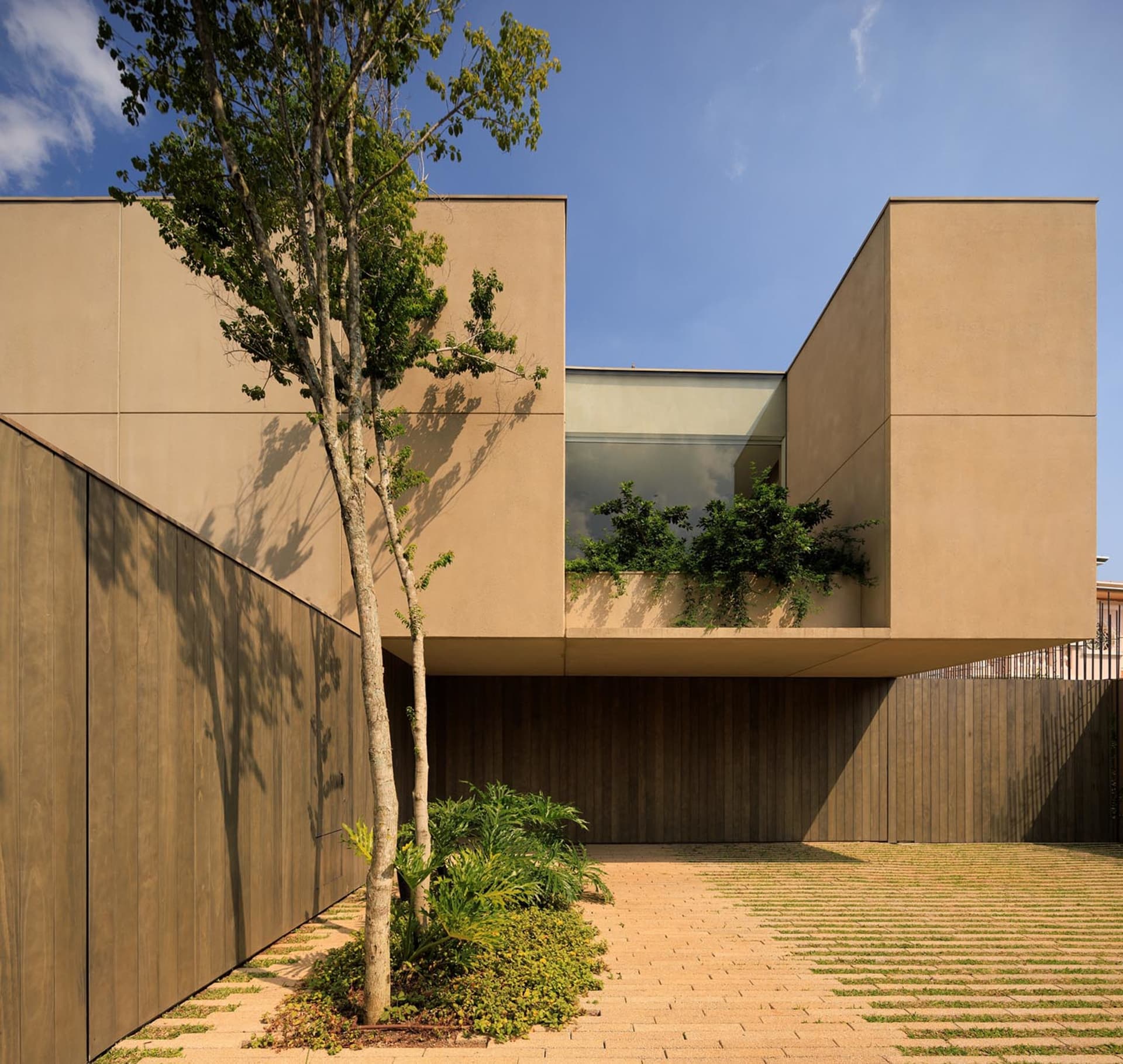 Modern residential exterior featuring sandstone and glass materials.