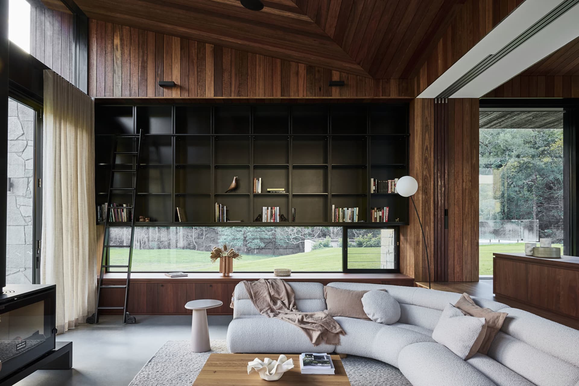 Modern living room with wood-paneled walls, a concrete floor, and a corner sofa.