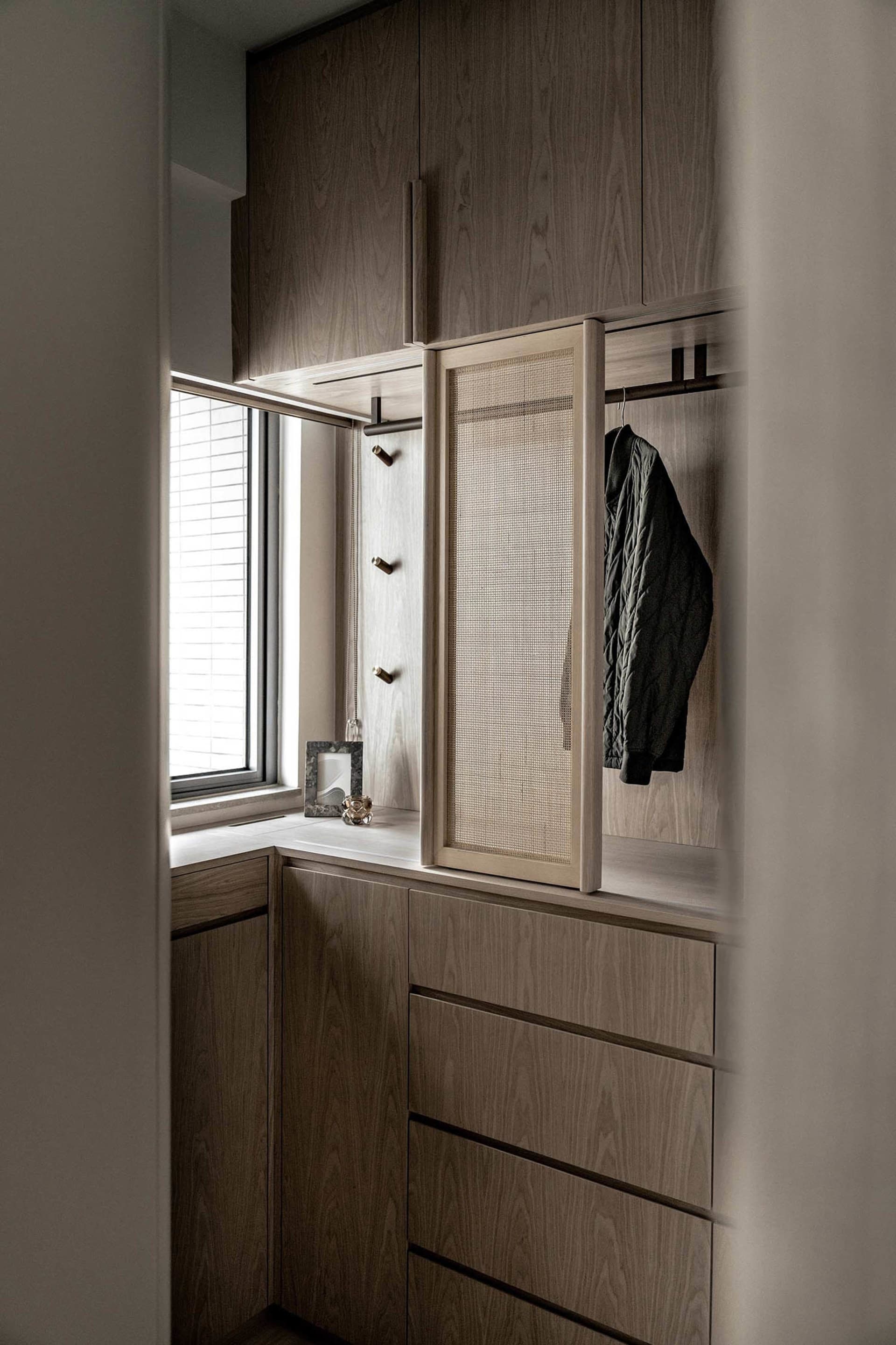 A modern wardrobe system with wooden storage units and a mesh-covered mirror.