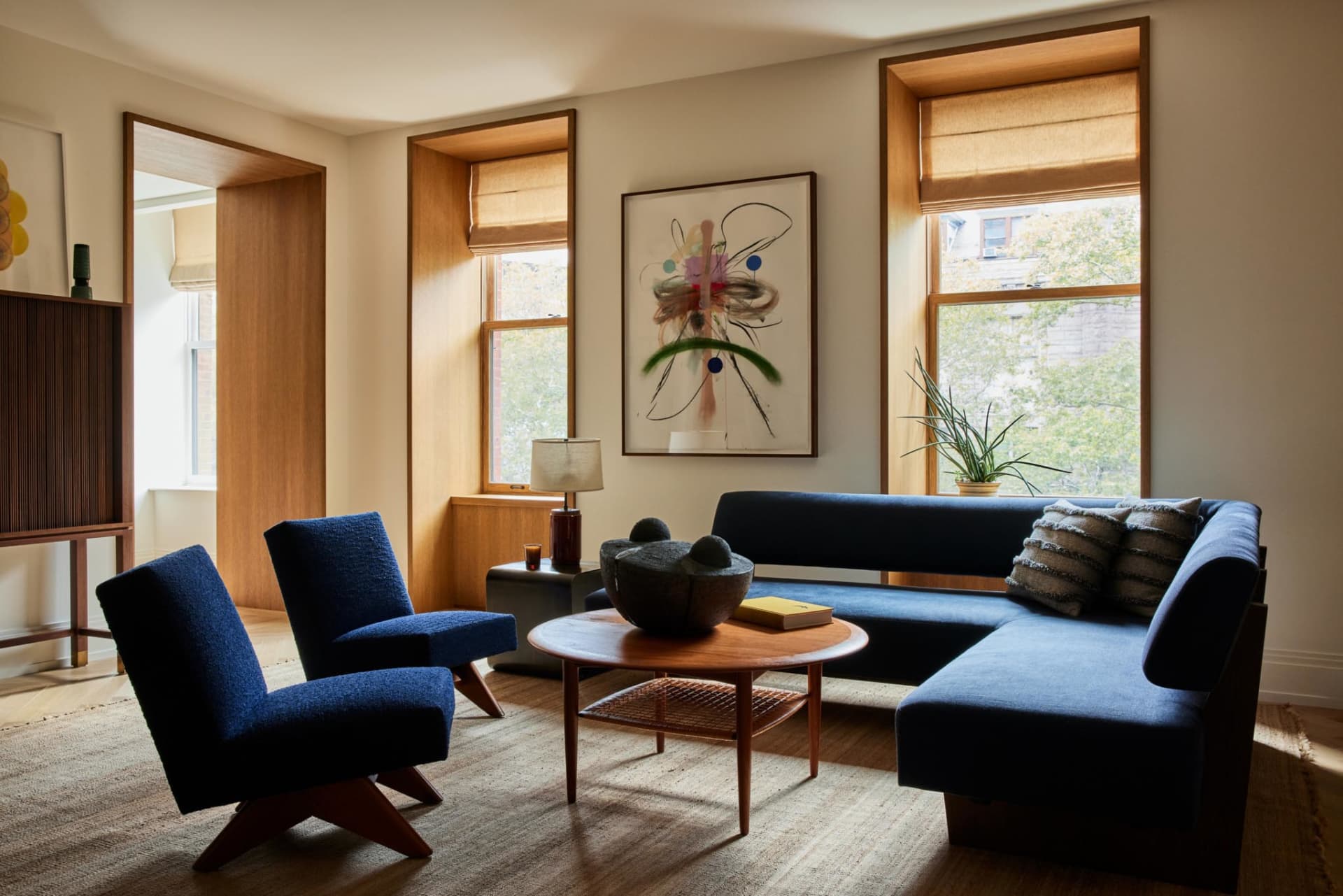 Modern living room featuring wooden furniture, a blue couch, and a coffee table with decorative items.