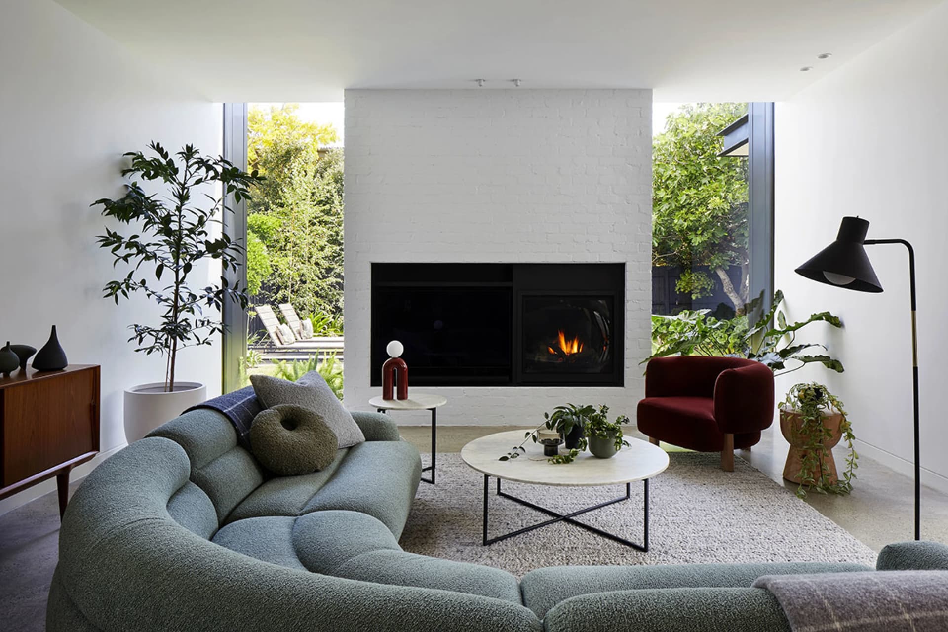 A modern living room featuring a green couch, coffee table, and fireplace.