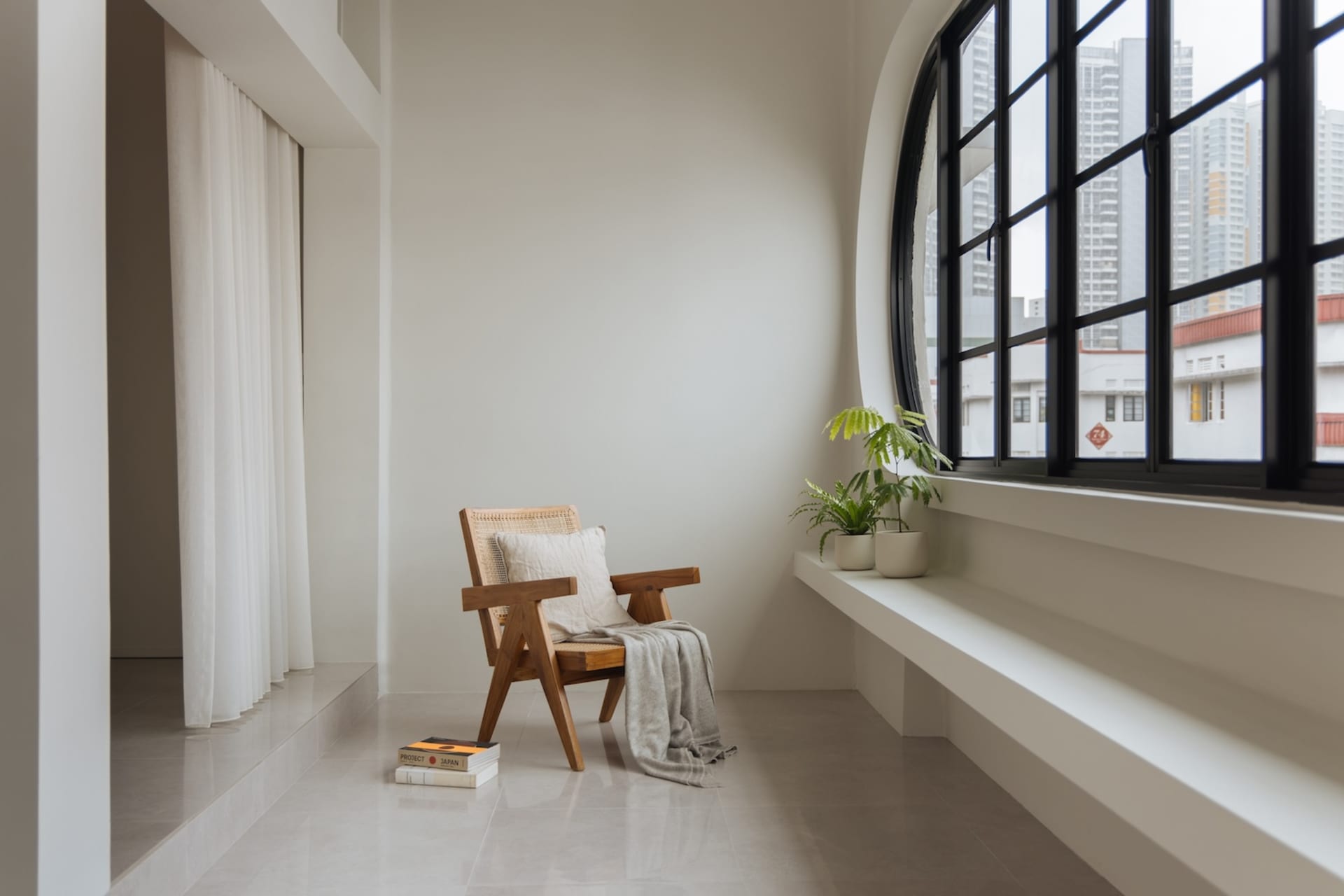 A minimalist living room with a window, a wooden chair, and green plants