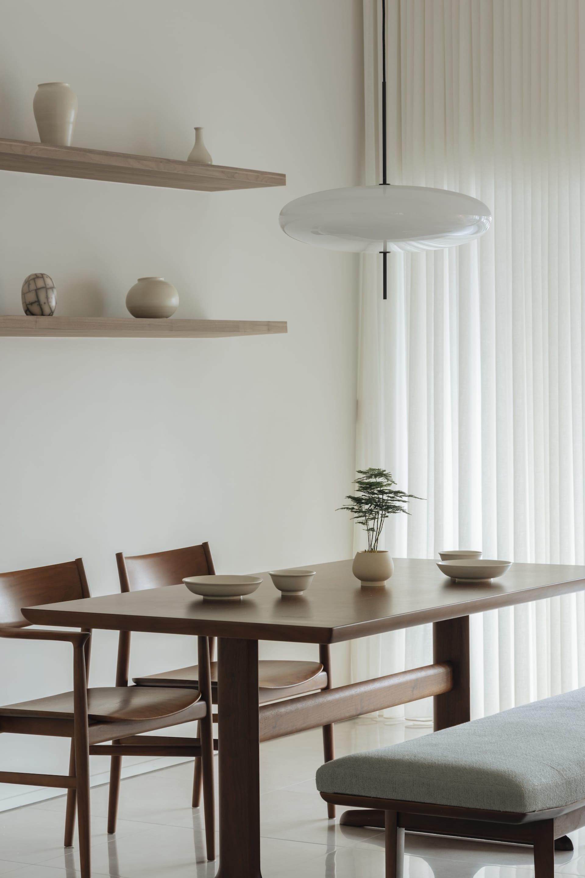 A modern dining room featuring wooden tables, glass vases, and fabric seating.