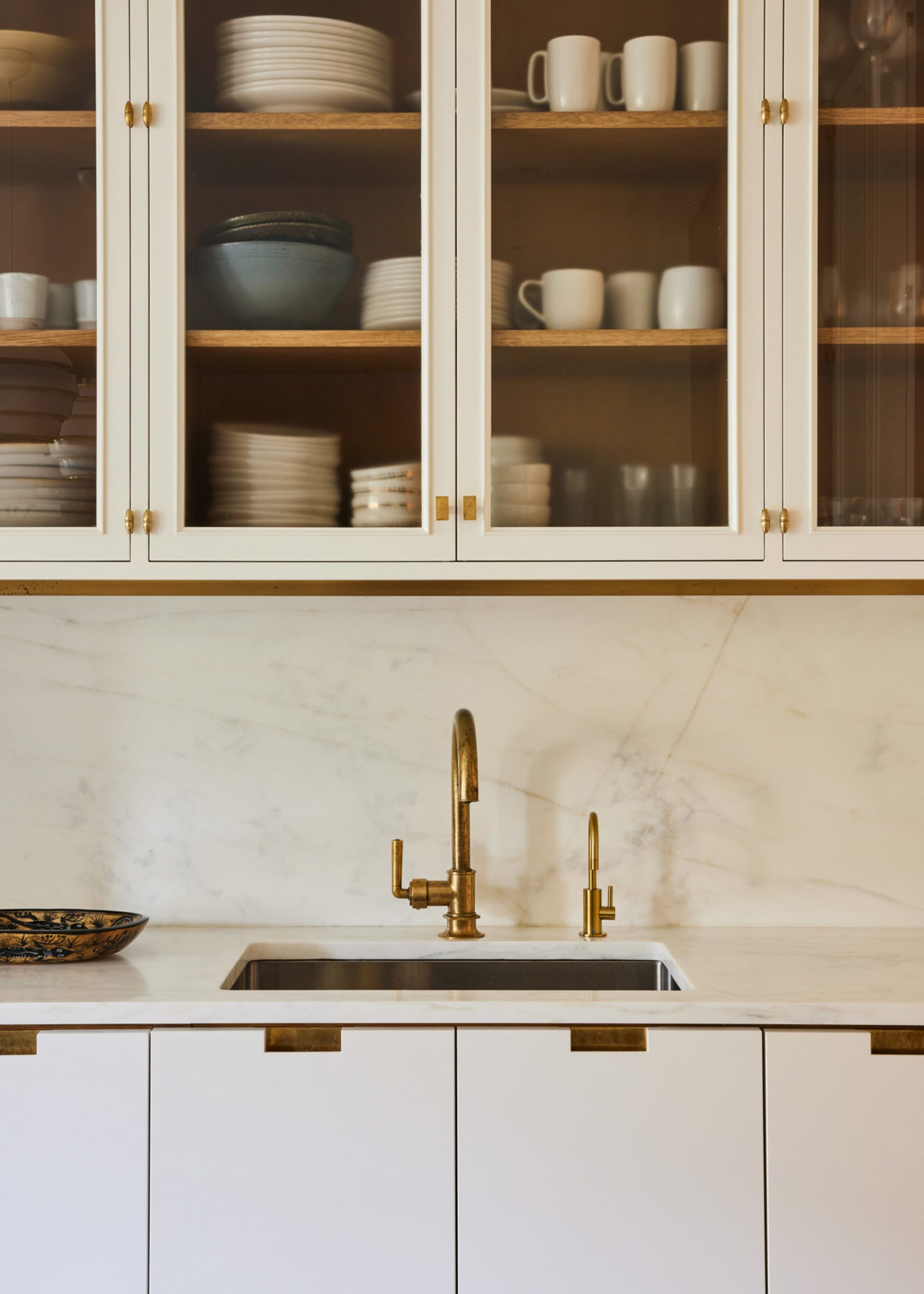 A modern kitchen featuring marble countertops and brass fixtures.
