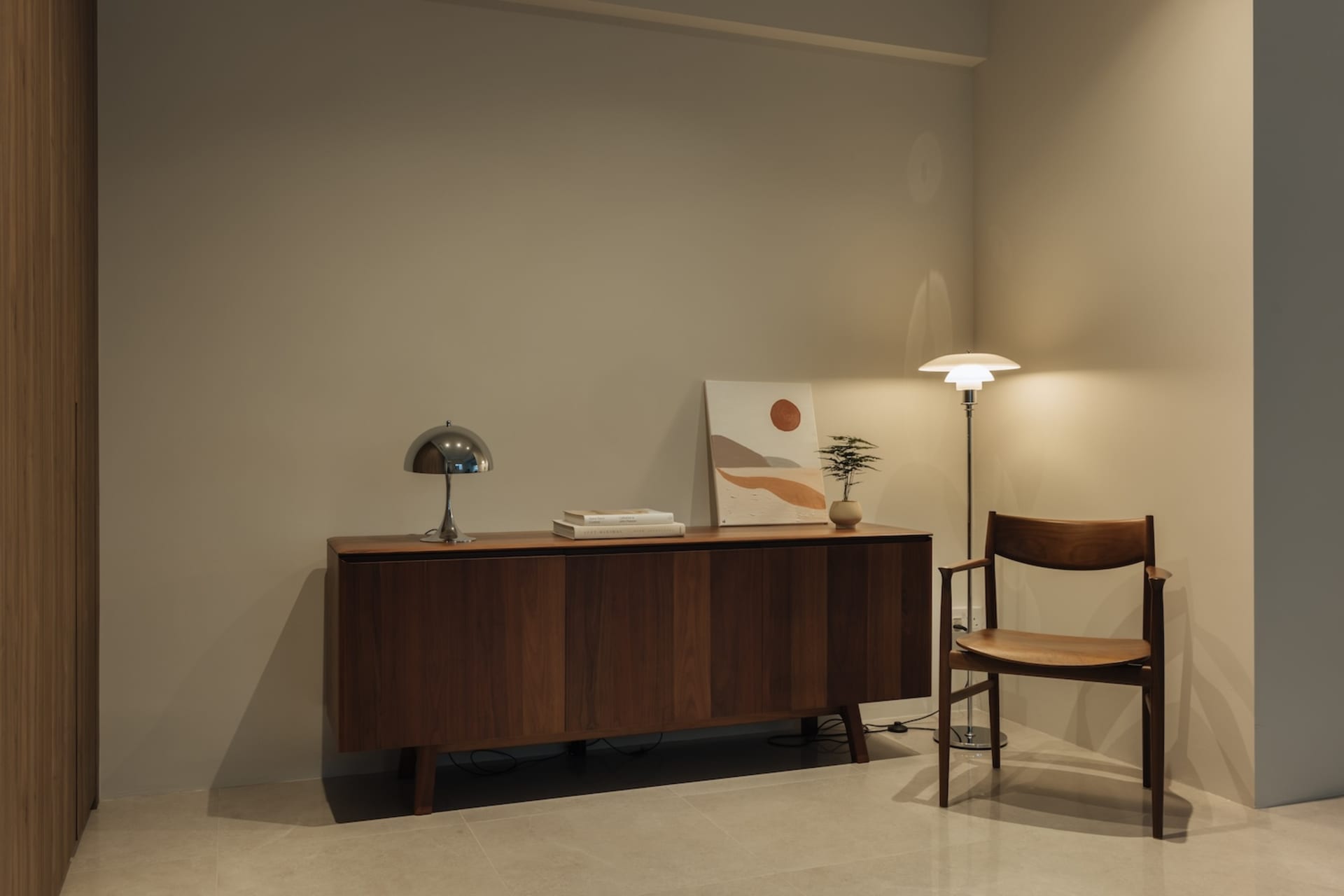 A modern living room featuring wooden furniture, a wooden sideboard with books and a plant, and a floor lamp.
