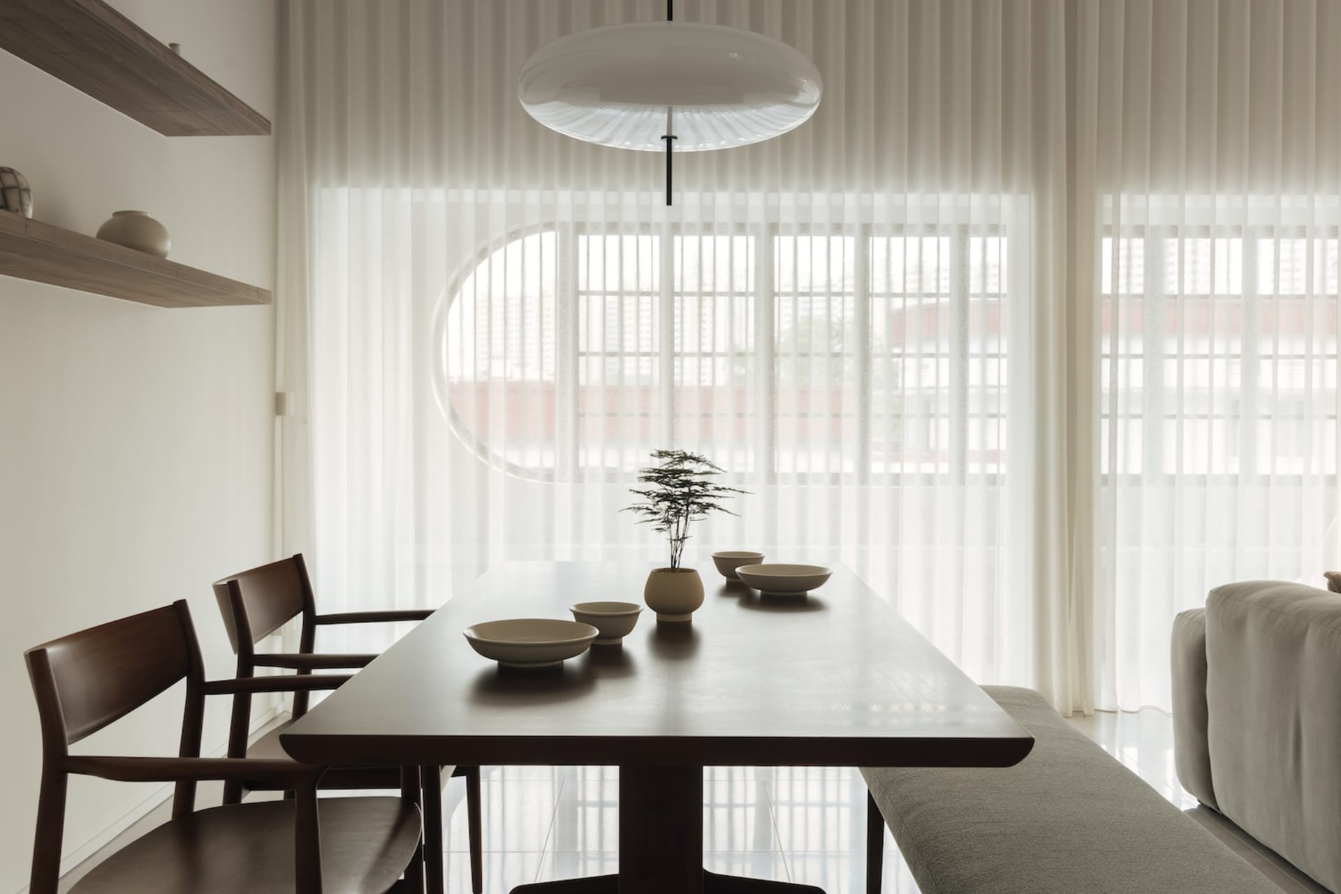 A modern, minimalist dining room features a wooden table, chairs, and bowls.
