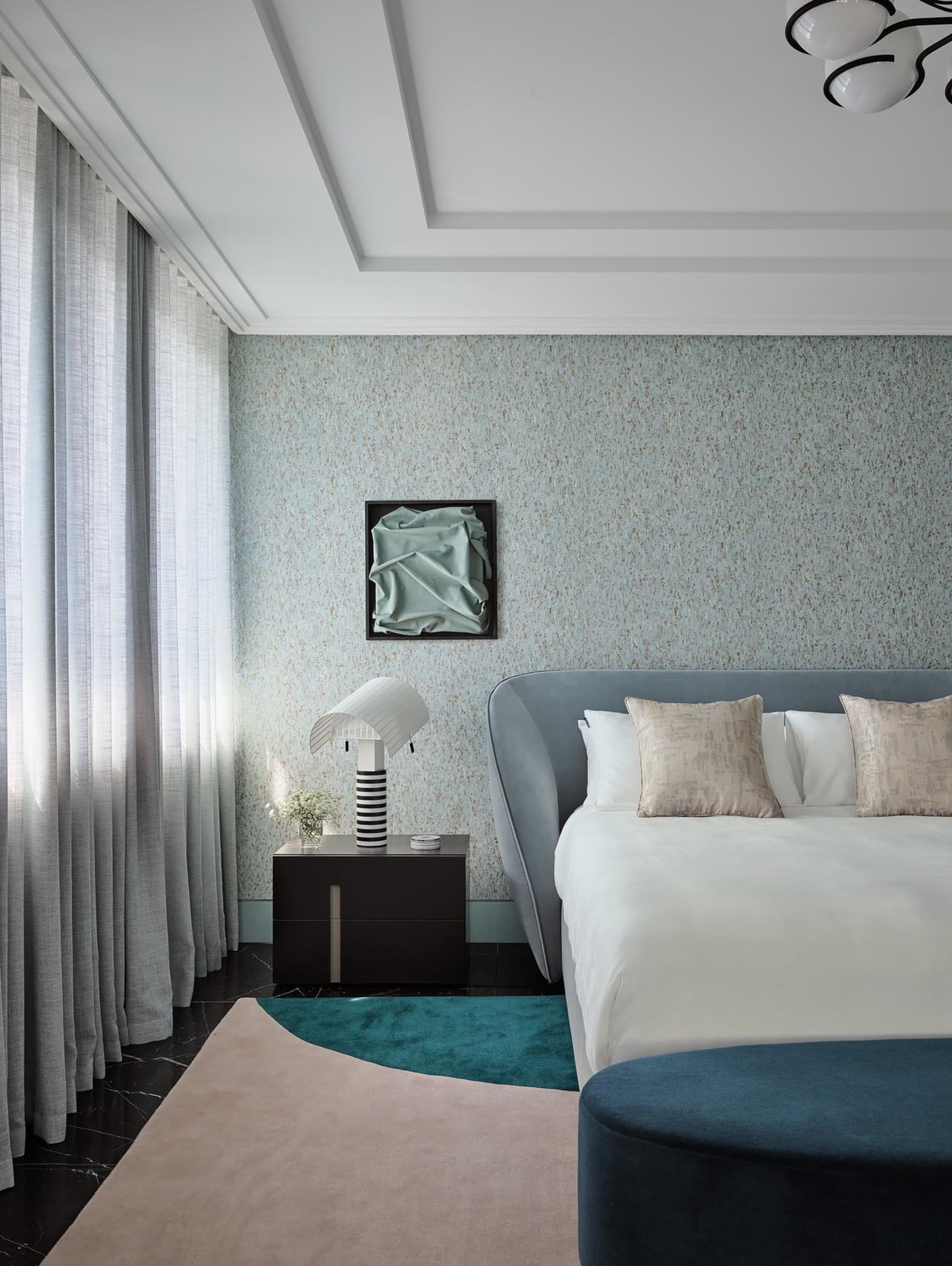 Modern bedroom with a large bed, glass wall, and smooth fabric bedspread.