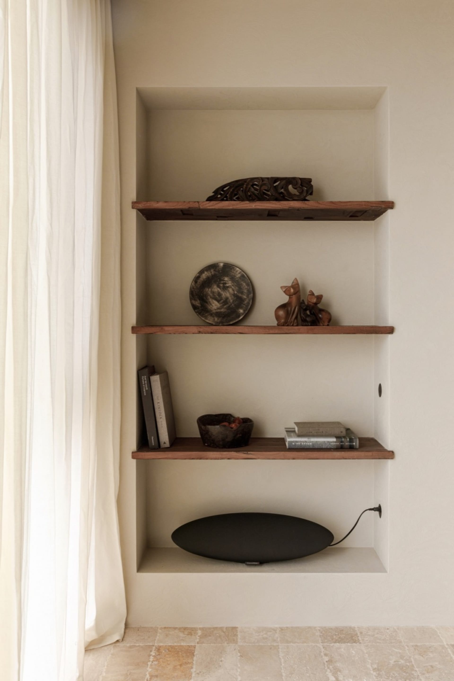 Three wooden shelves with rustic decor items such as a plate, figurines, and books.