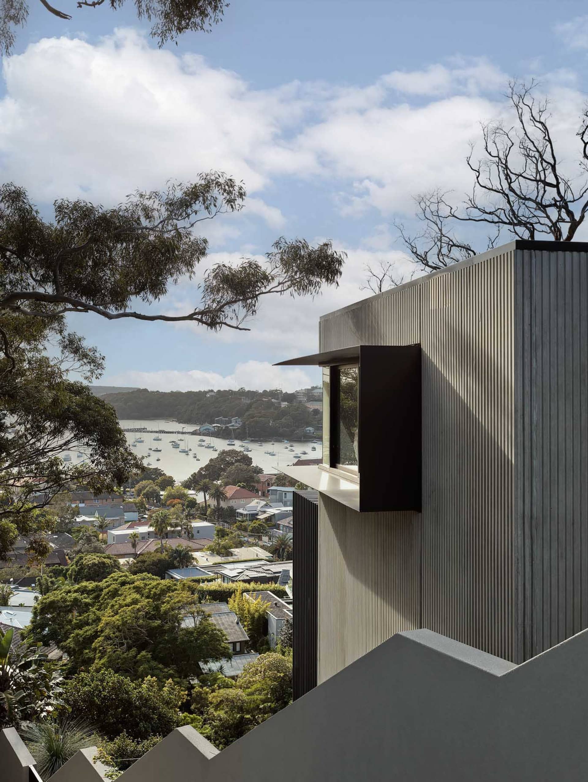 A modern building with a metallic exterior overlooking a bay with boats.