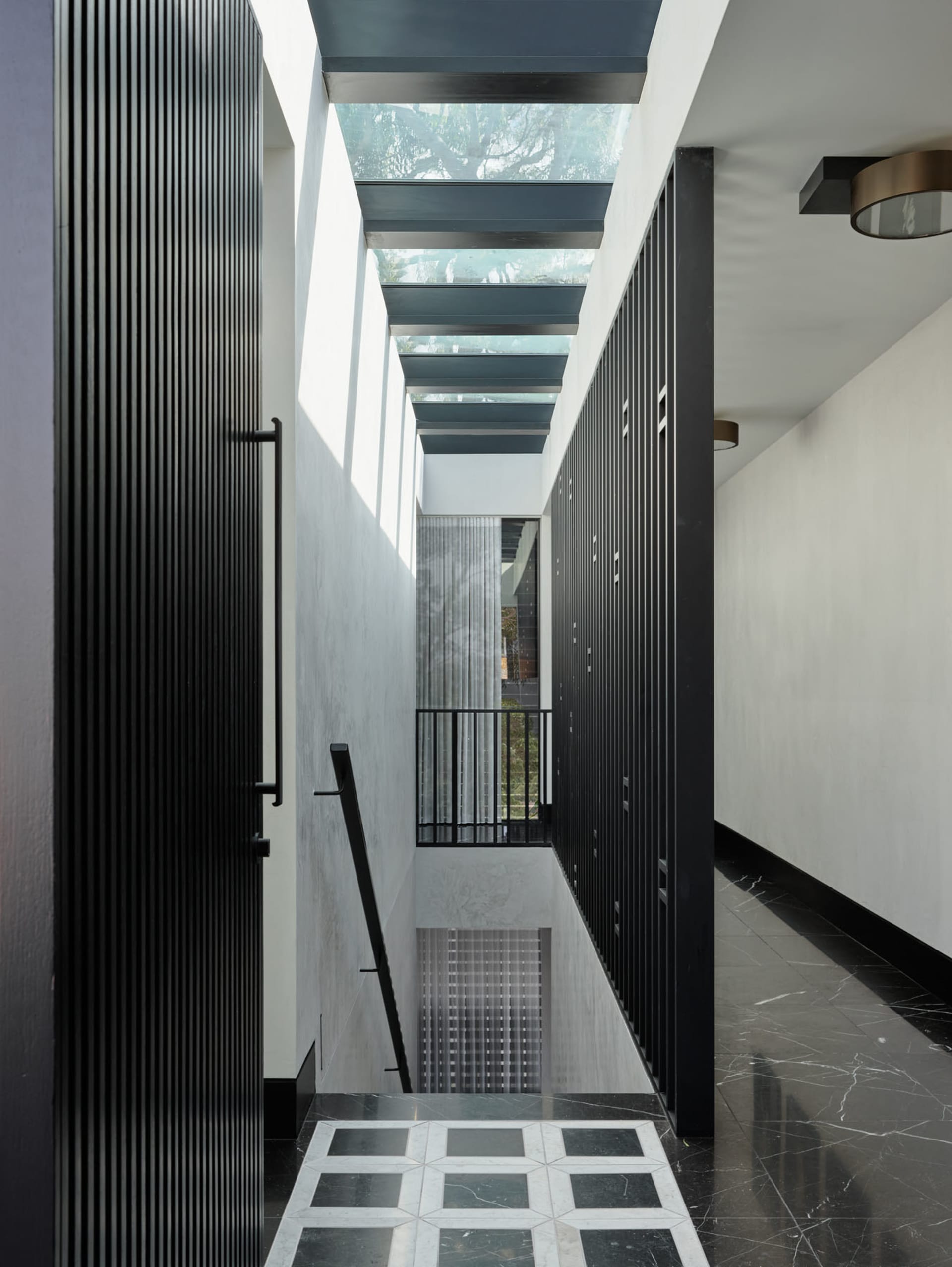 A modern interior design featuring glass ceiling, black columns, and marble flooring.
