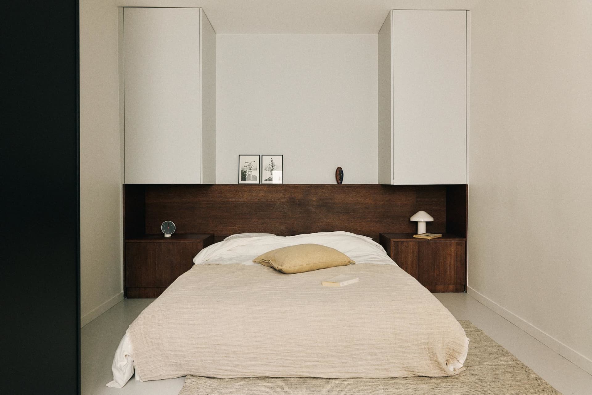 Minimalist bedroom with a wooden bed and white bedding.