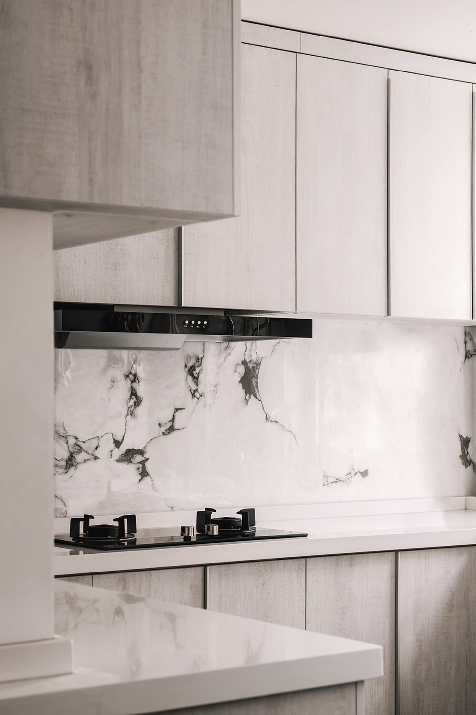 Modern kitchen with white marble backsplash and white wooden cabinets