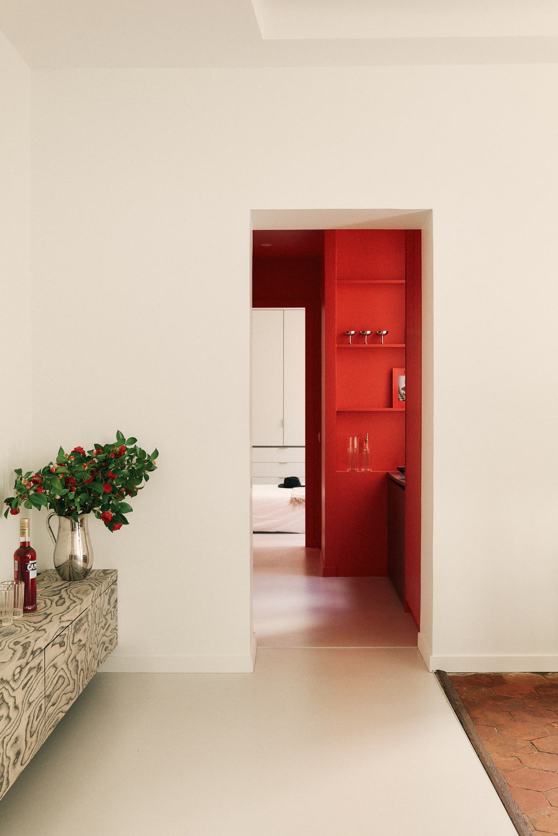 A modern living room with white walls and a red door.