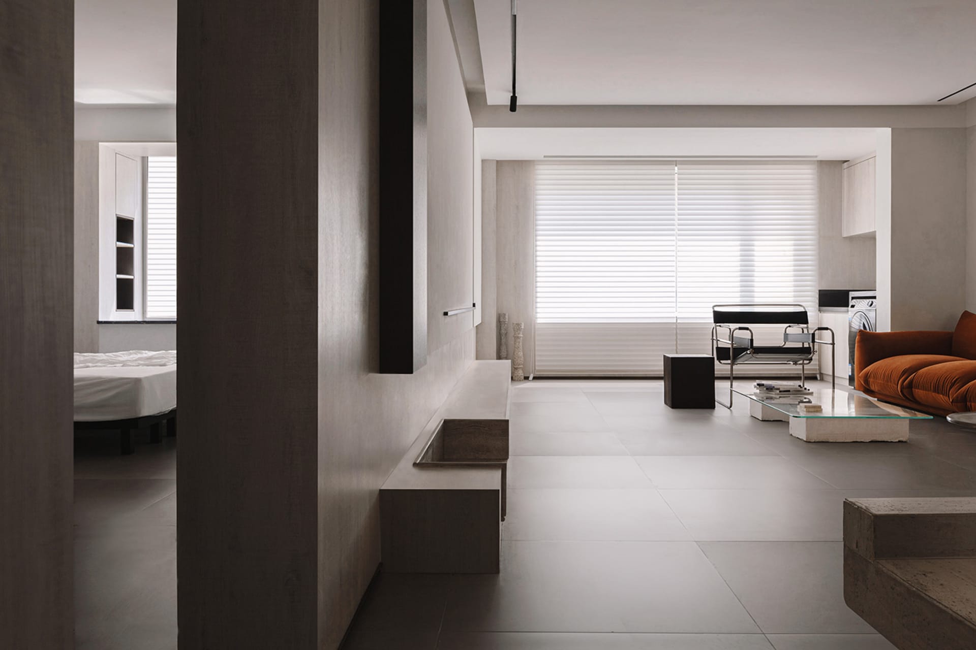 A modern minimalist living room with concrete walls, floor, and furniture, featuring a minimalist sofa, a coffee table, and a