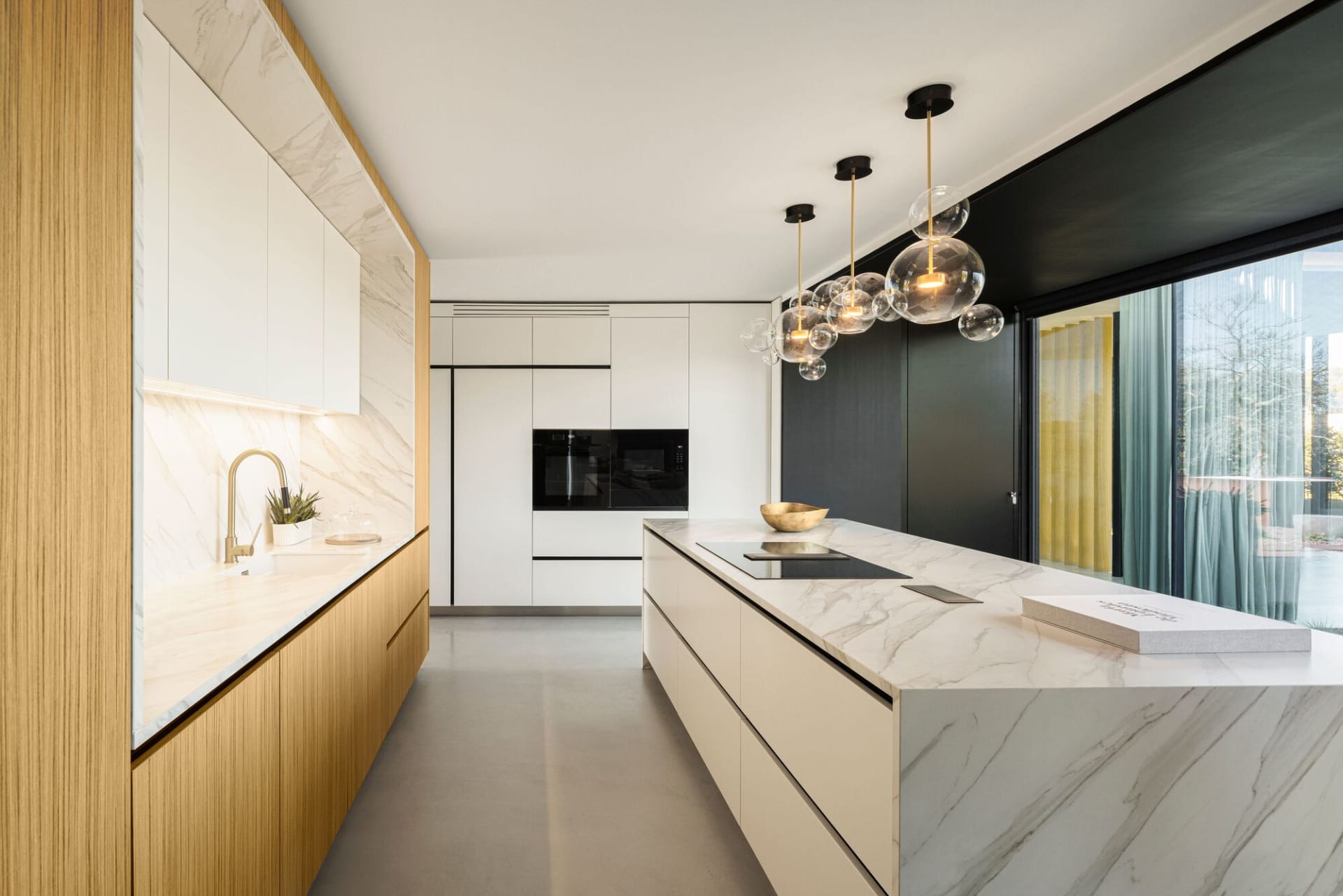 Modern kitchen featuring marble countertops, wooden cabinets, and a glass pendant light fixture.