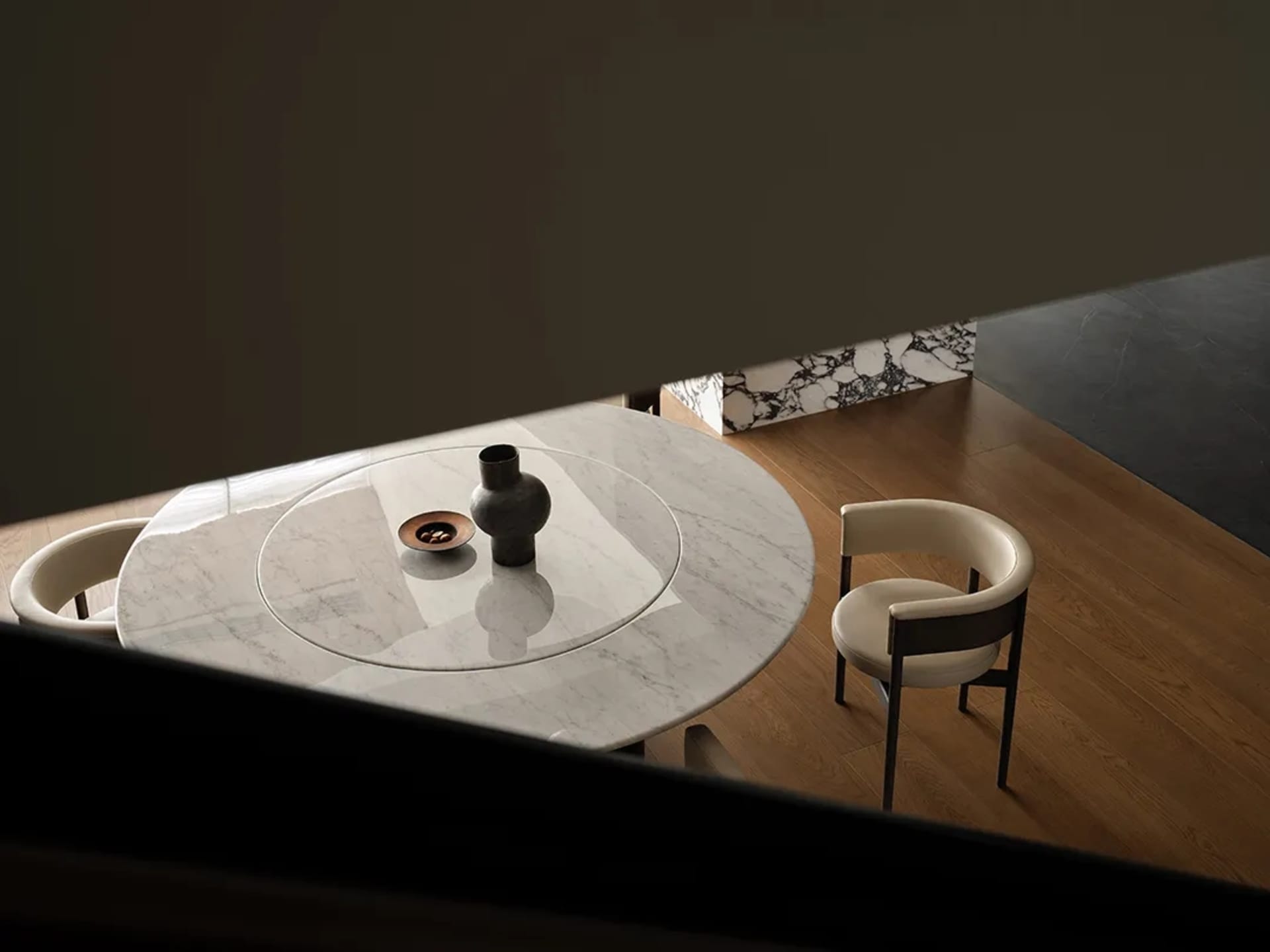 Minimalist dining room with marble table top and walnut chairs, featuring a vase and bowl centerpiece.