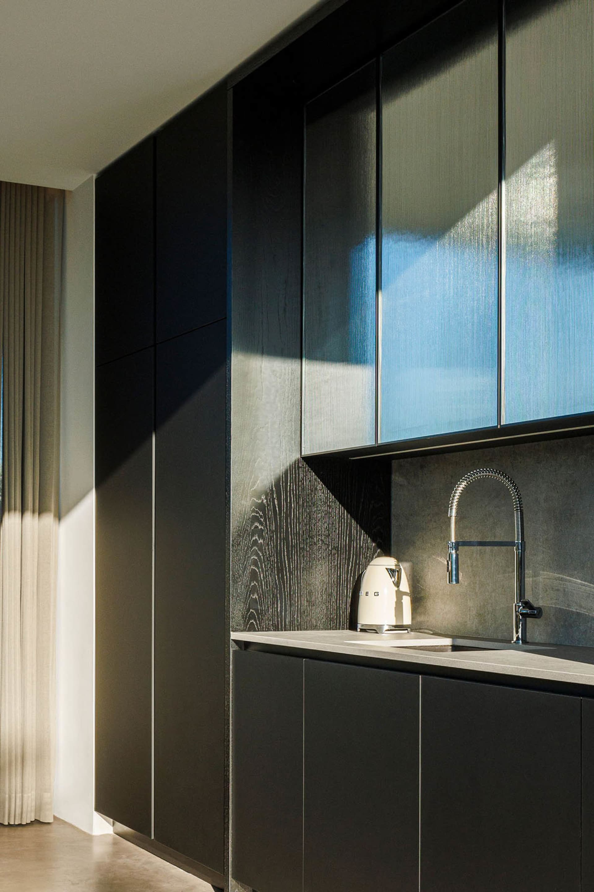 A modern kitchen with black wooden cabinets and a sleek, minimalist design.