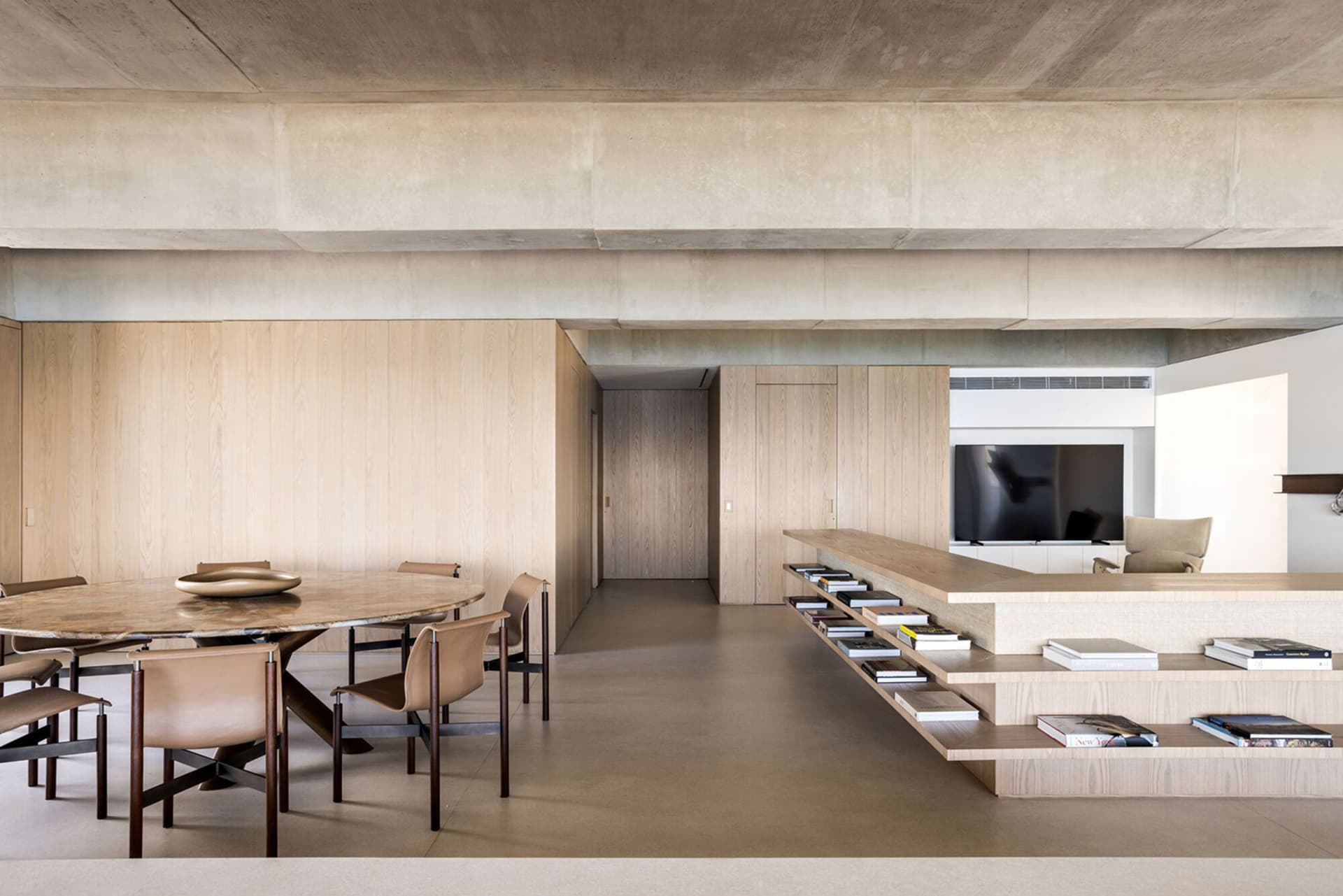 A minimalist living room with a concrete ceiling, wooden walls, and a marble table.