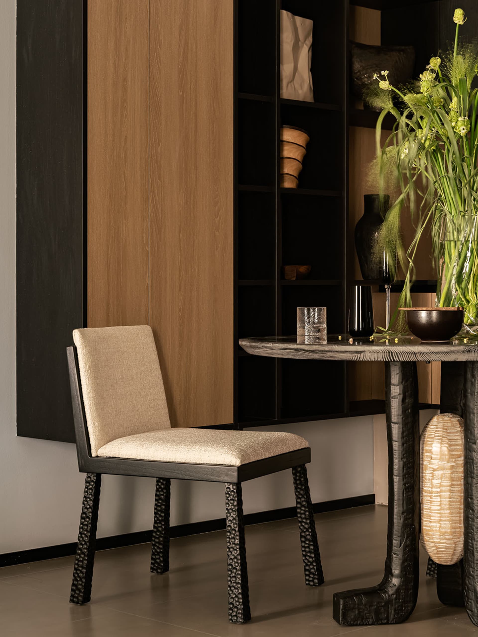 A modern black dining chair with a beige upholstered seat and cushioned backrest.