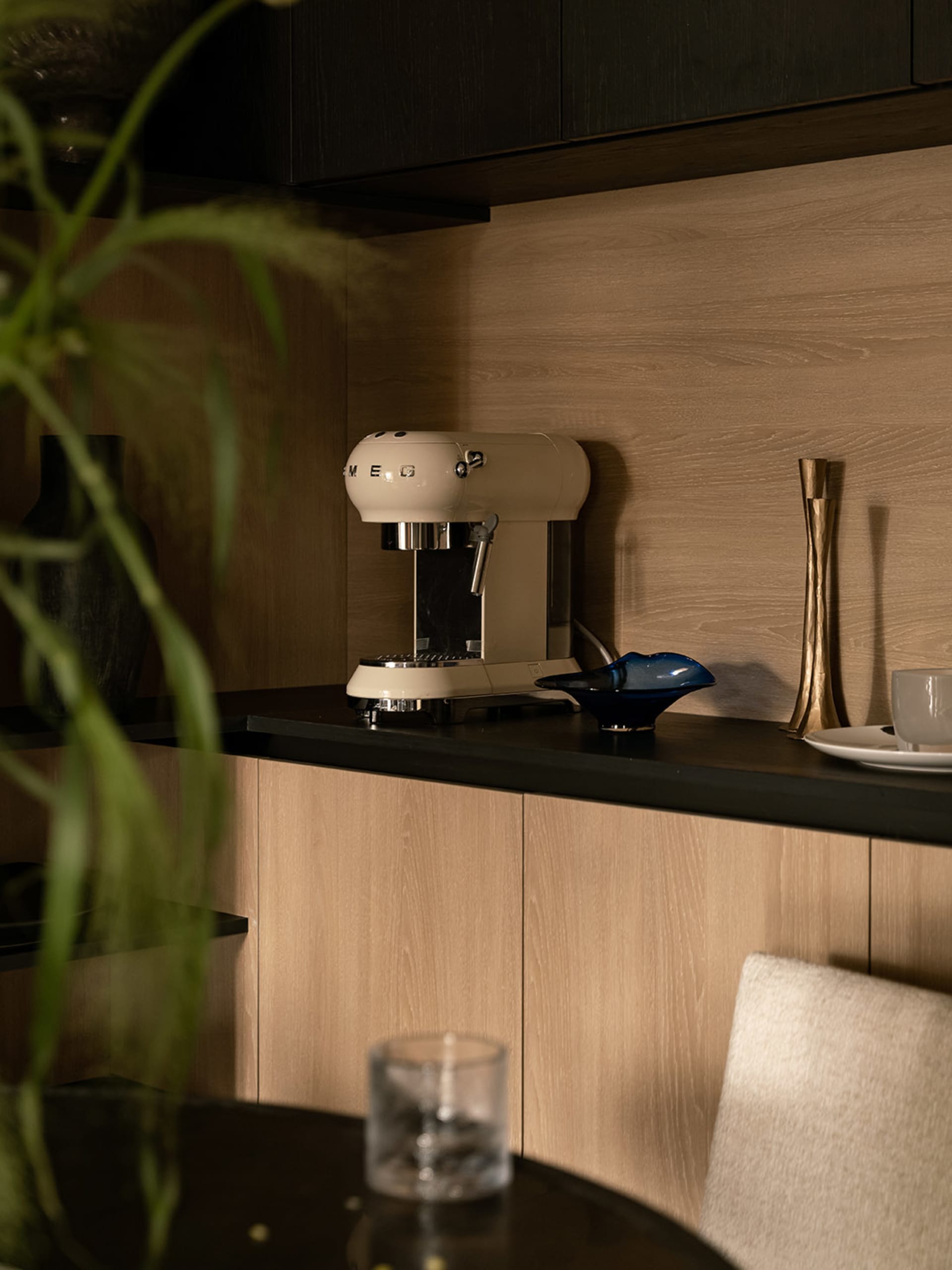 Modern kitchen featuring a beige espresso machine on a wooden countertop with a blue bowl and a white vase.