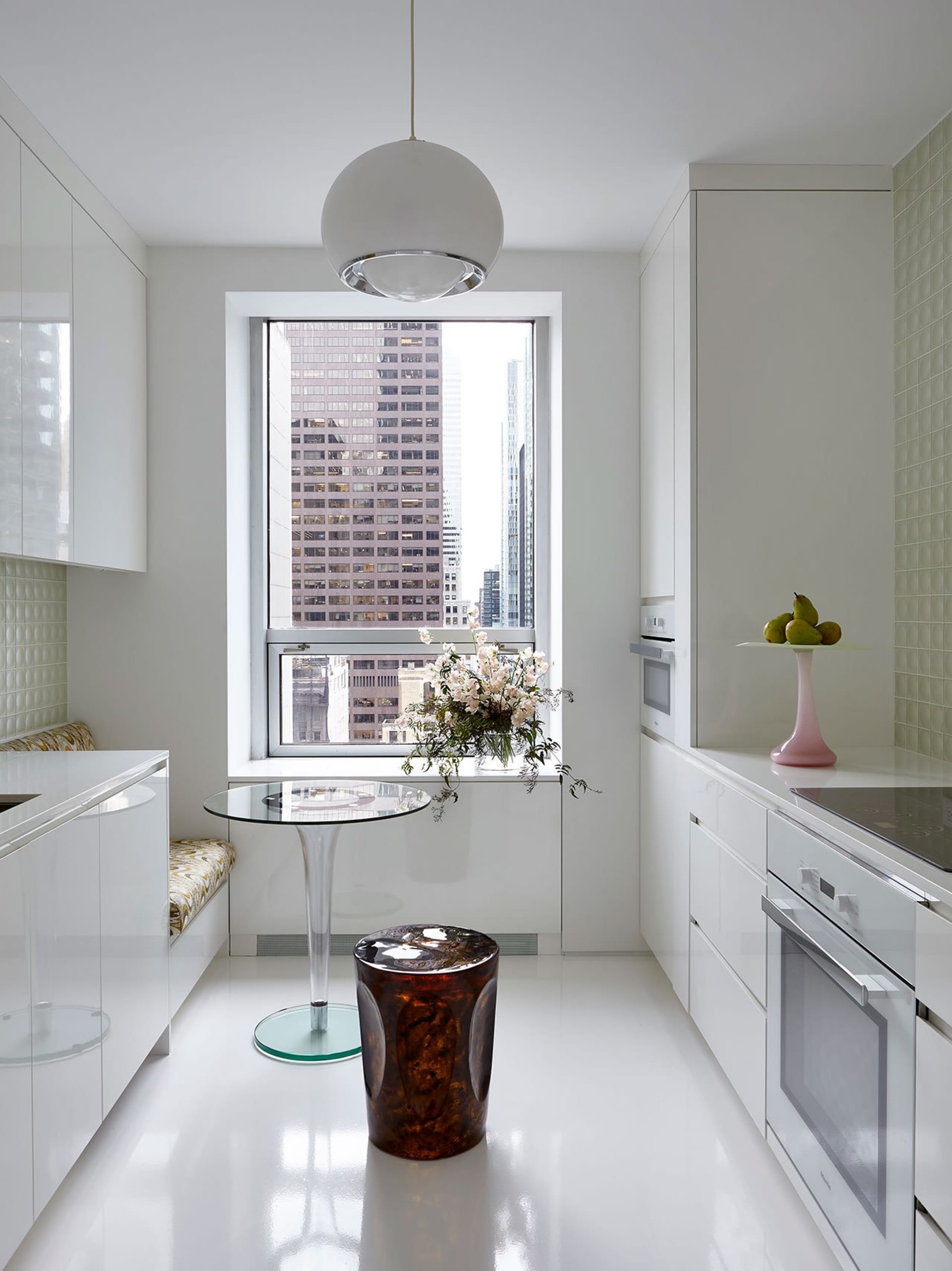A modern kitchen with white cabinets and a window overlooking a cityscape.