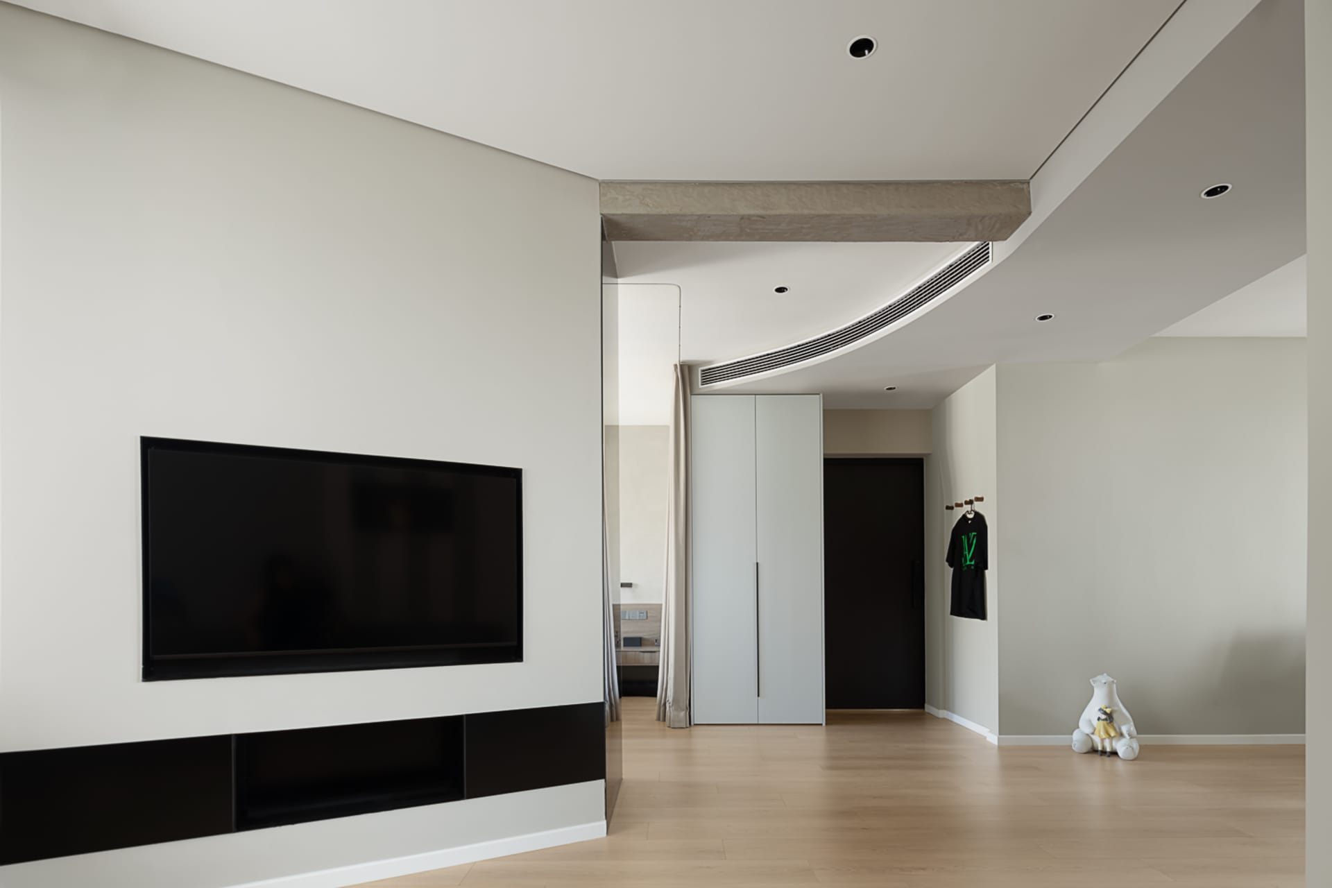 A modern living room with light wooden flooring, white walls, and a minimalist design.