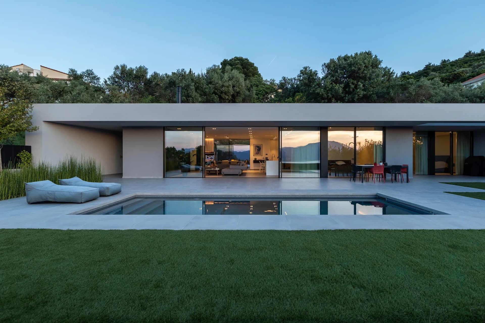 A modern residential home with a concrete facade and a pool in the backyard.