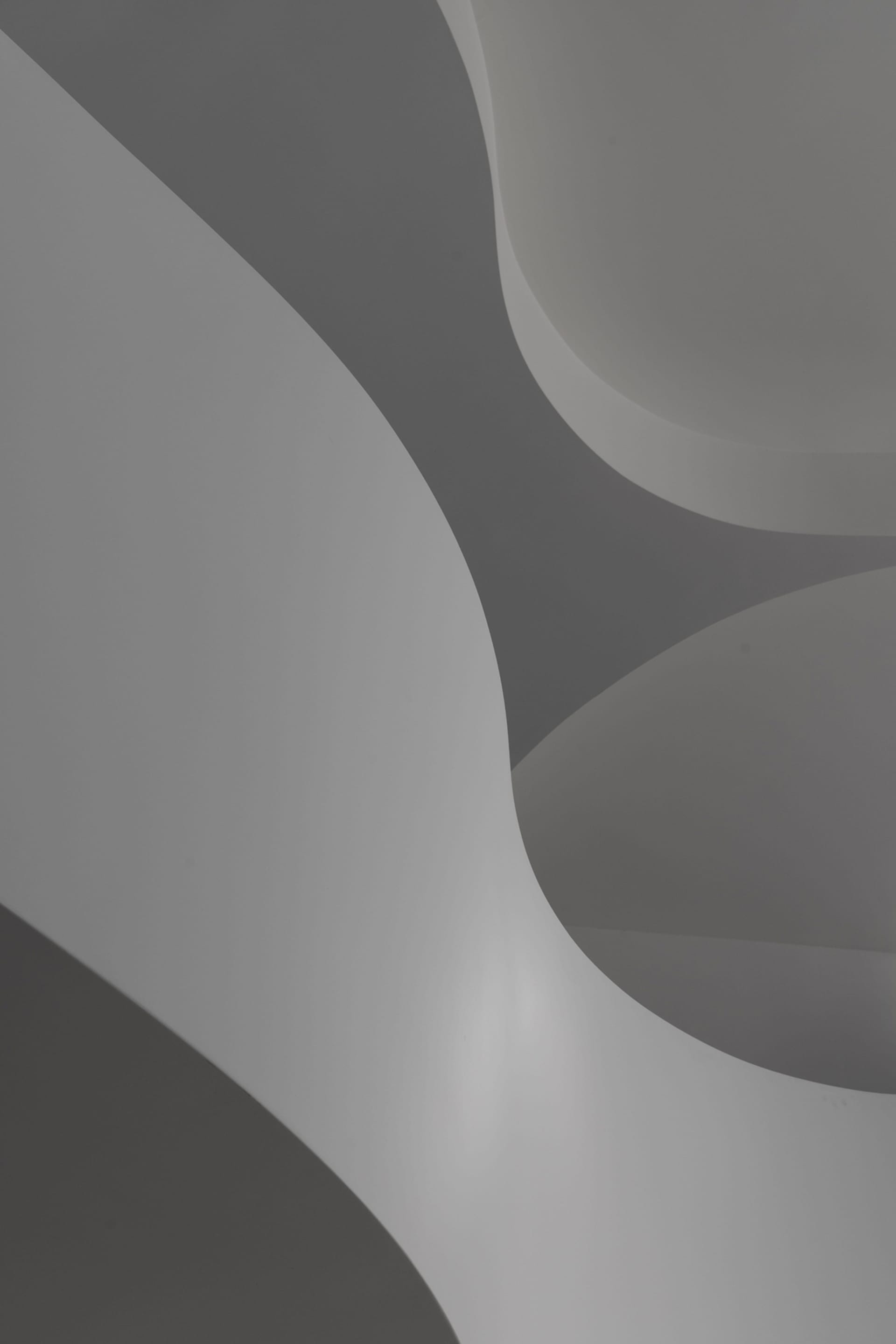 Grey concrete spiral staircase with smooth, curved steps and a continuous handrail.