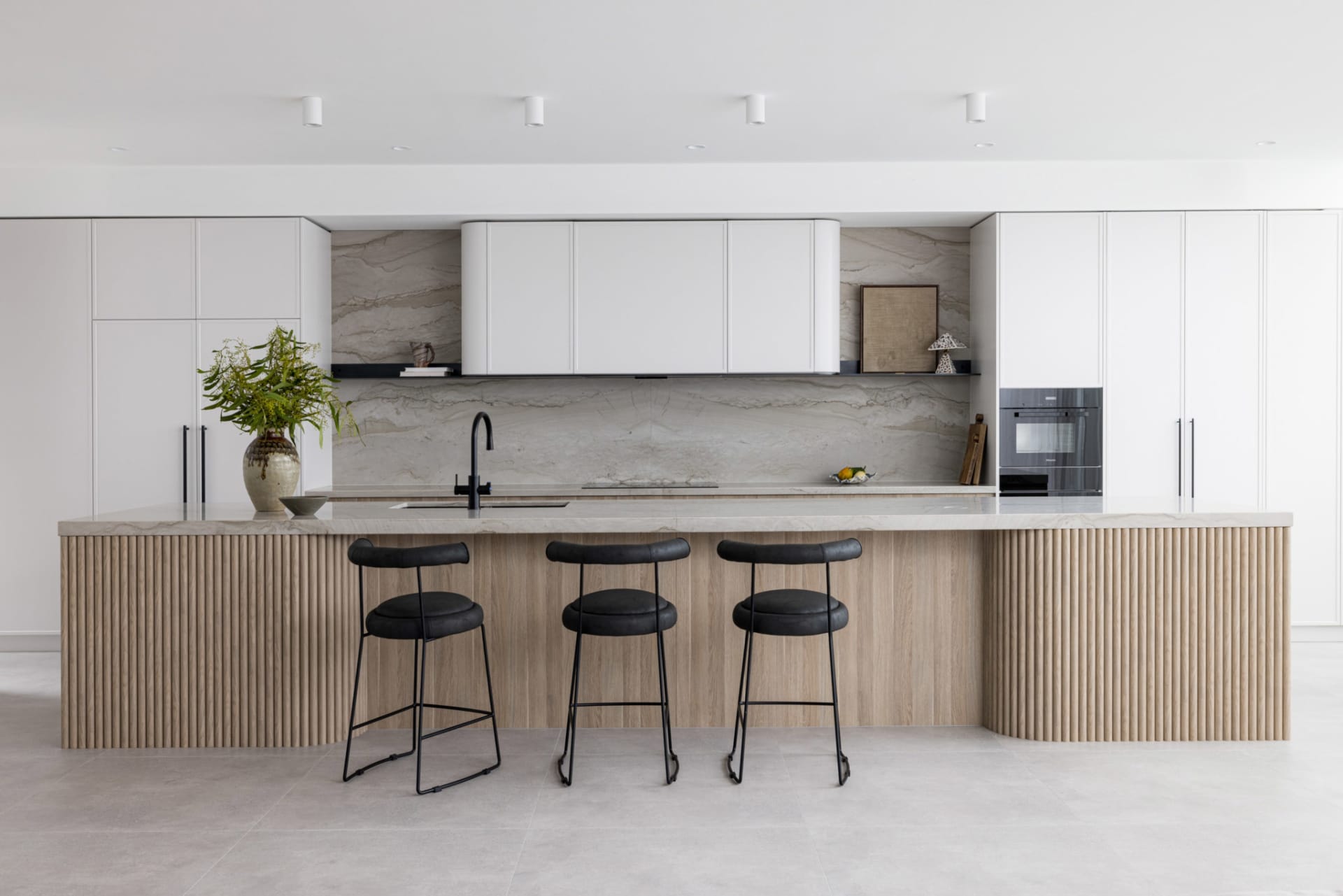 Contemporary residential kitchen featuring a marble countertop and bar stools.