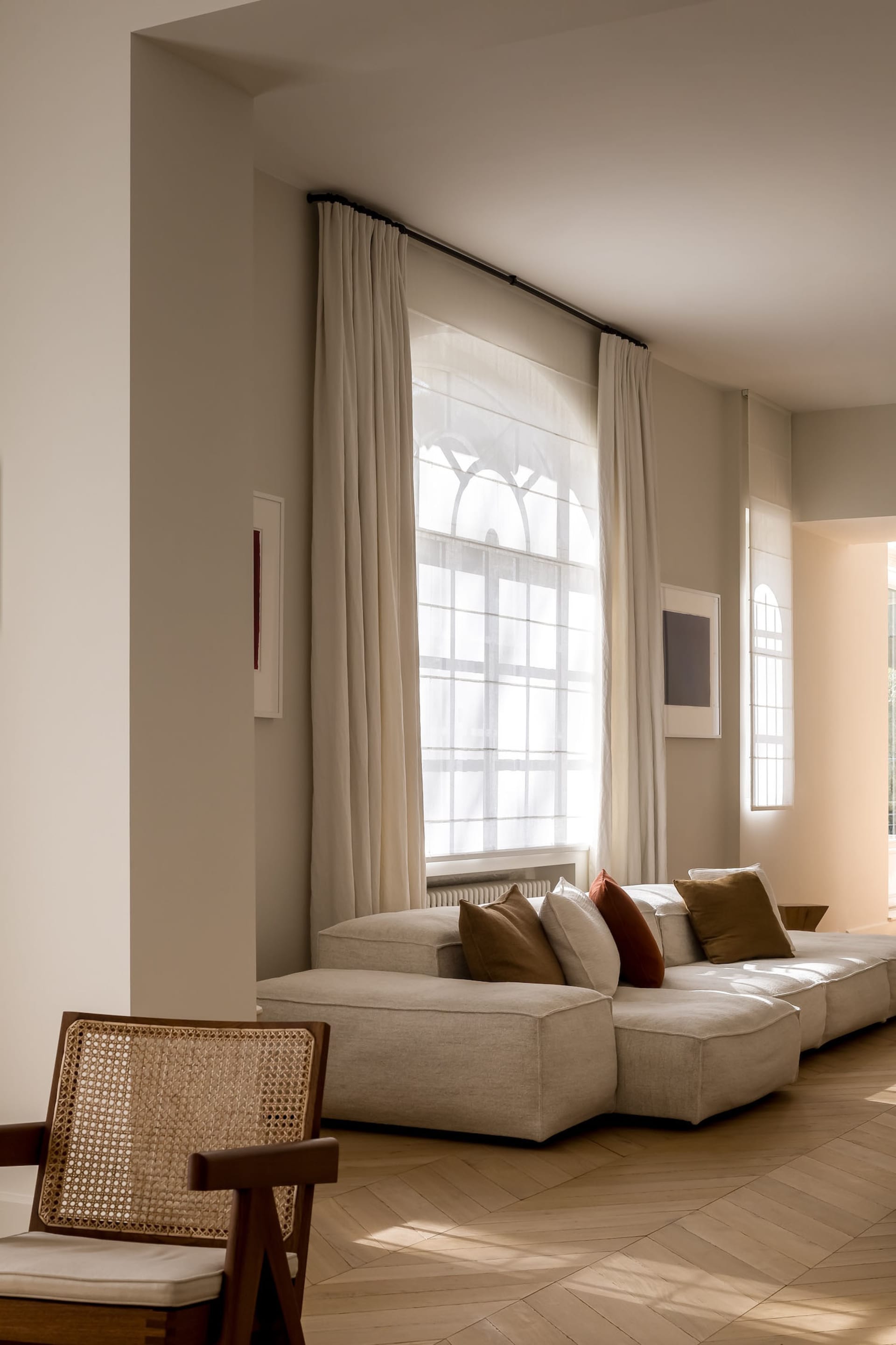 Modern living room with neutral-toned furniture and large windows.