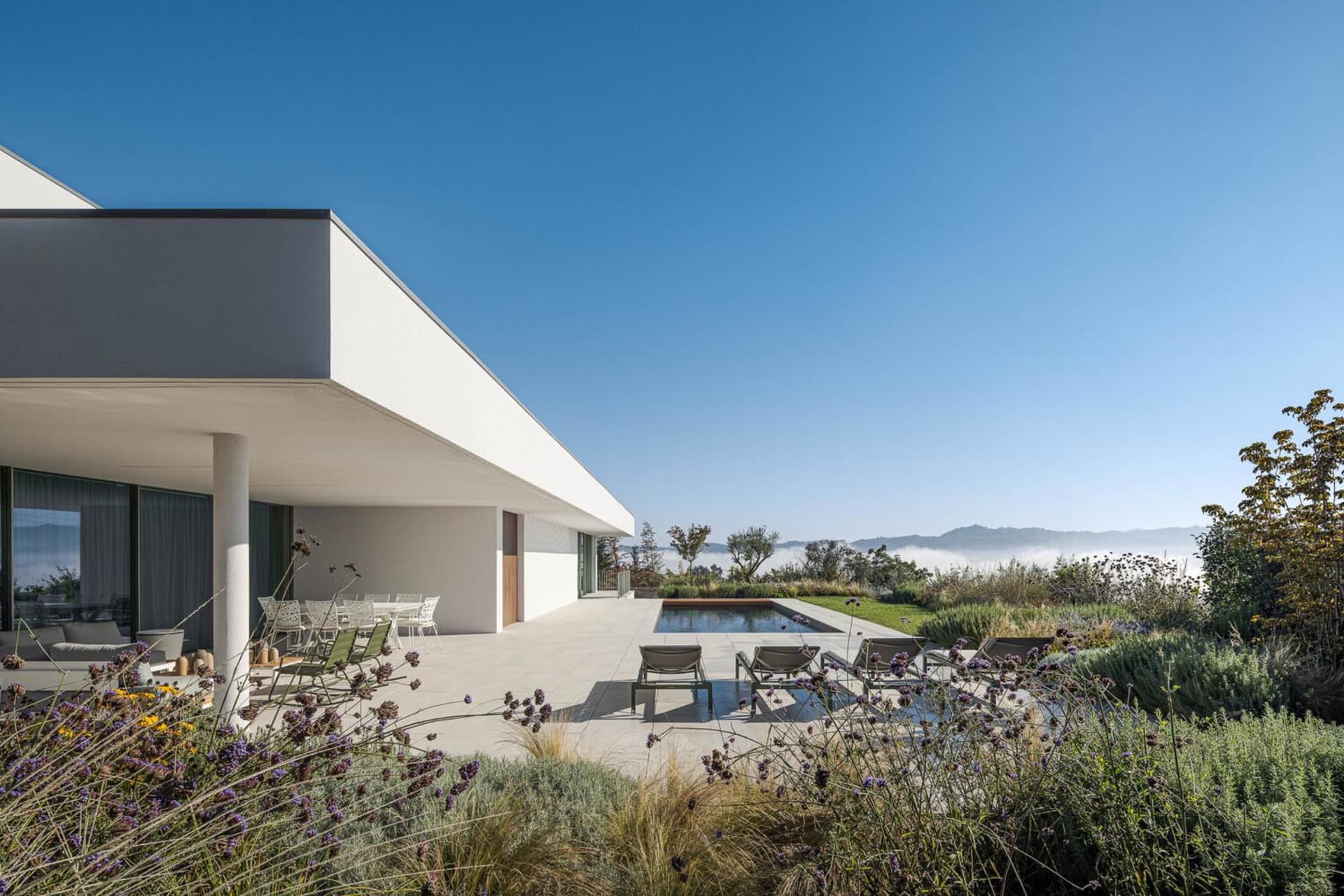 A modern minimalist residential space featuring concrete and glass elements.