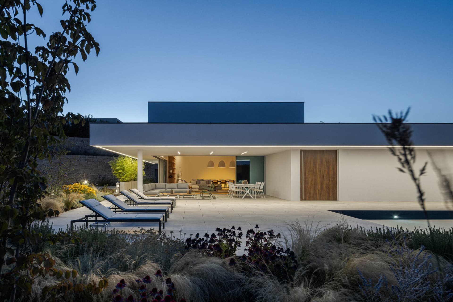 A modern residential exterior featuring concrete, glass, and metal materials.
