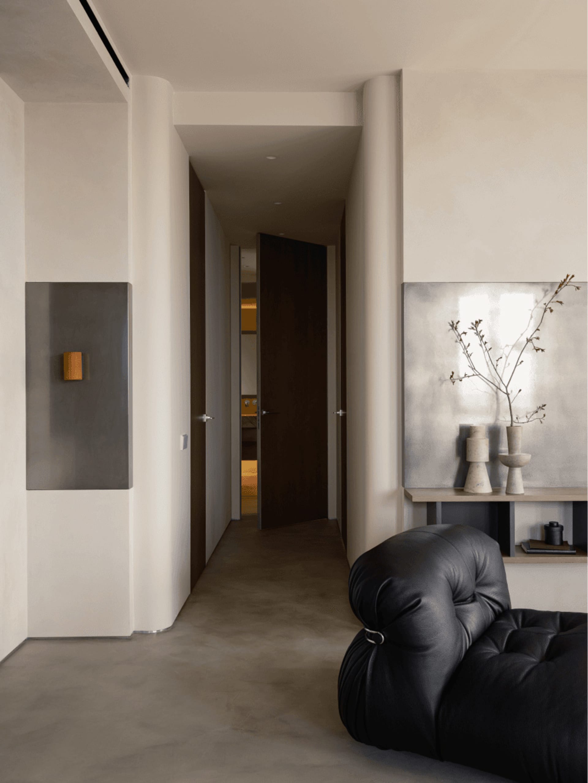 A modern residential interior featuring concrete, leather, and wood materials.
