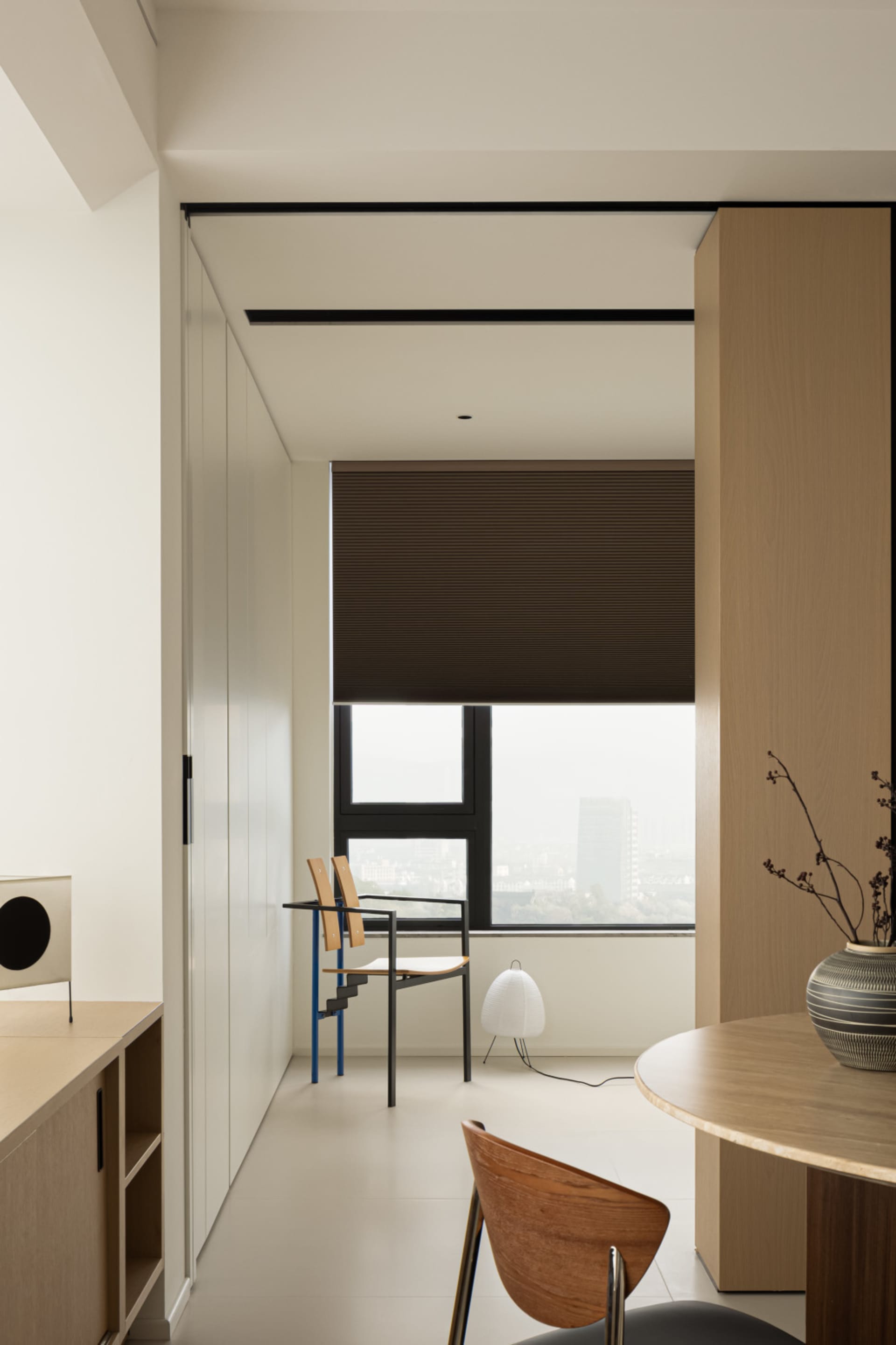 Modern minimalist living room featuring wooden furniture, a large window with blinds, and a sleek design.
