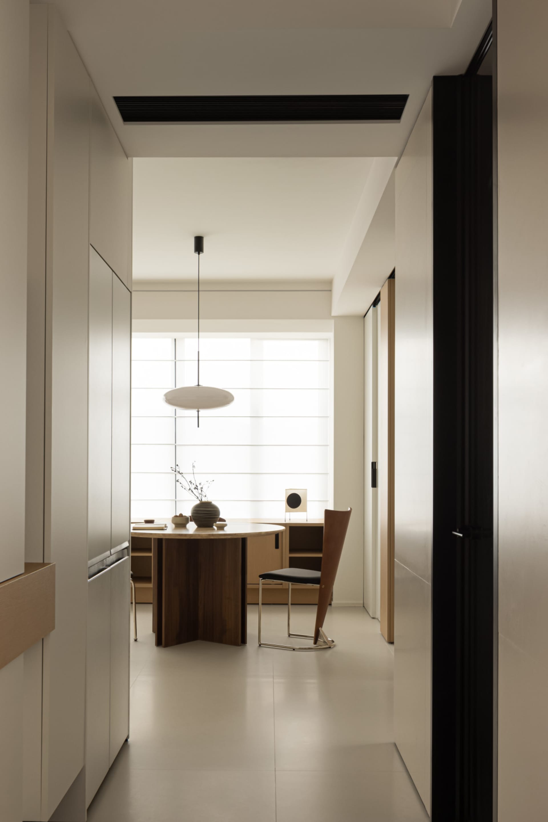 A modern dining room with a wooden table and white chairs, featuring a minimalist design and contemporary style.