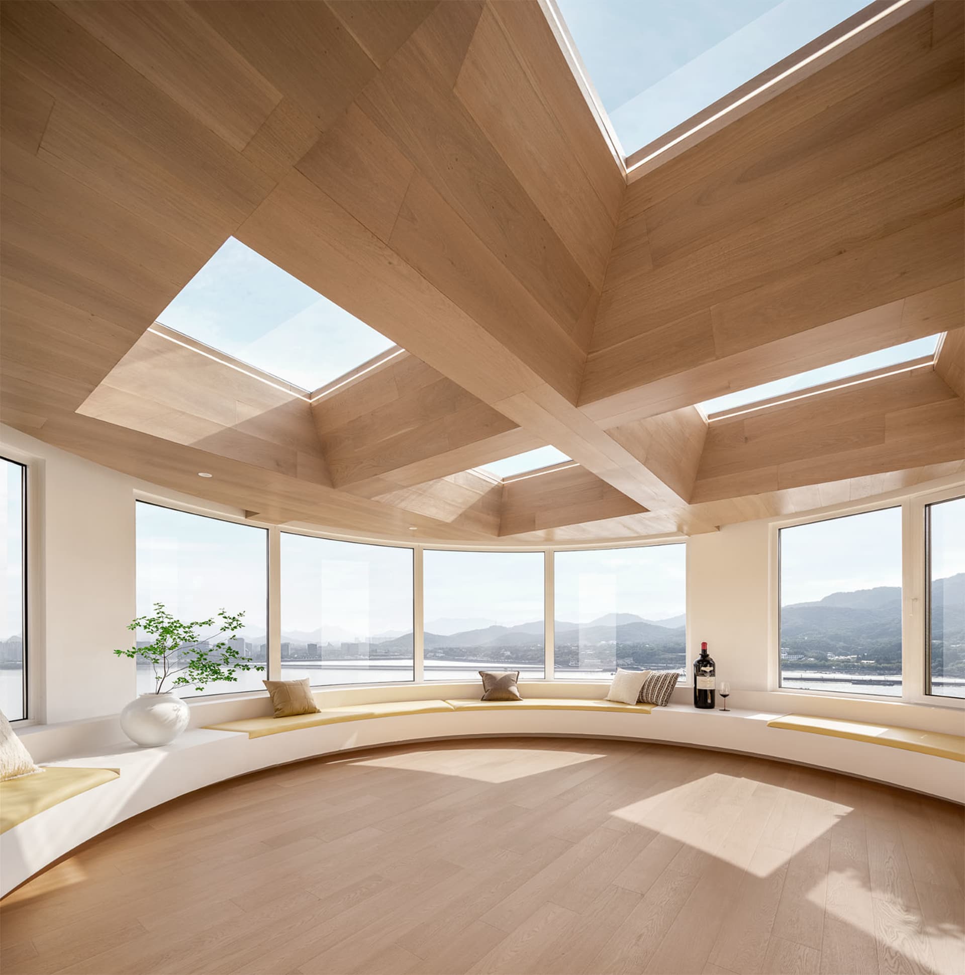 A modern living room with curved windows and wooden plank flooring.