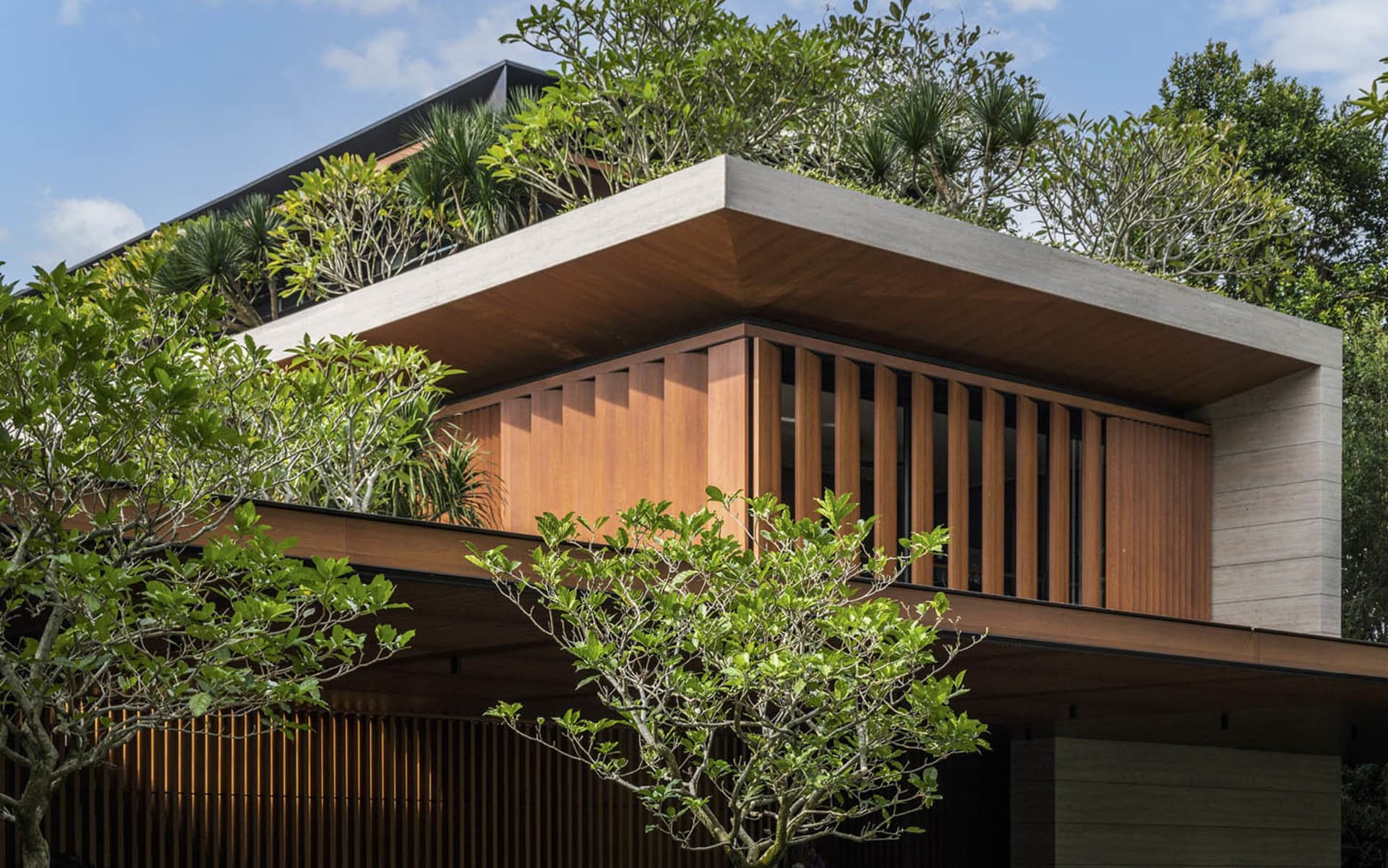 A modern residential building with wood and concrete exterior features a green, rooftop garden.