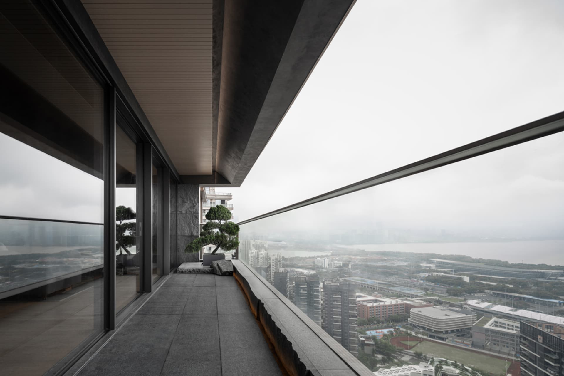 現代陽台俯瞰城市景觀,擺放一盆盆栽與戶外座椅。
