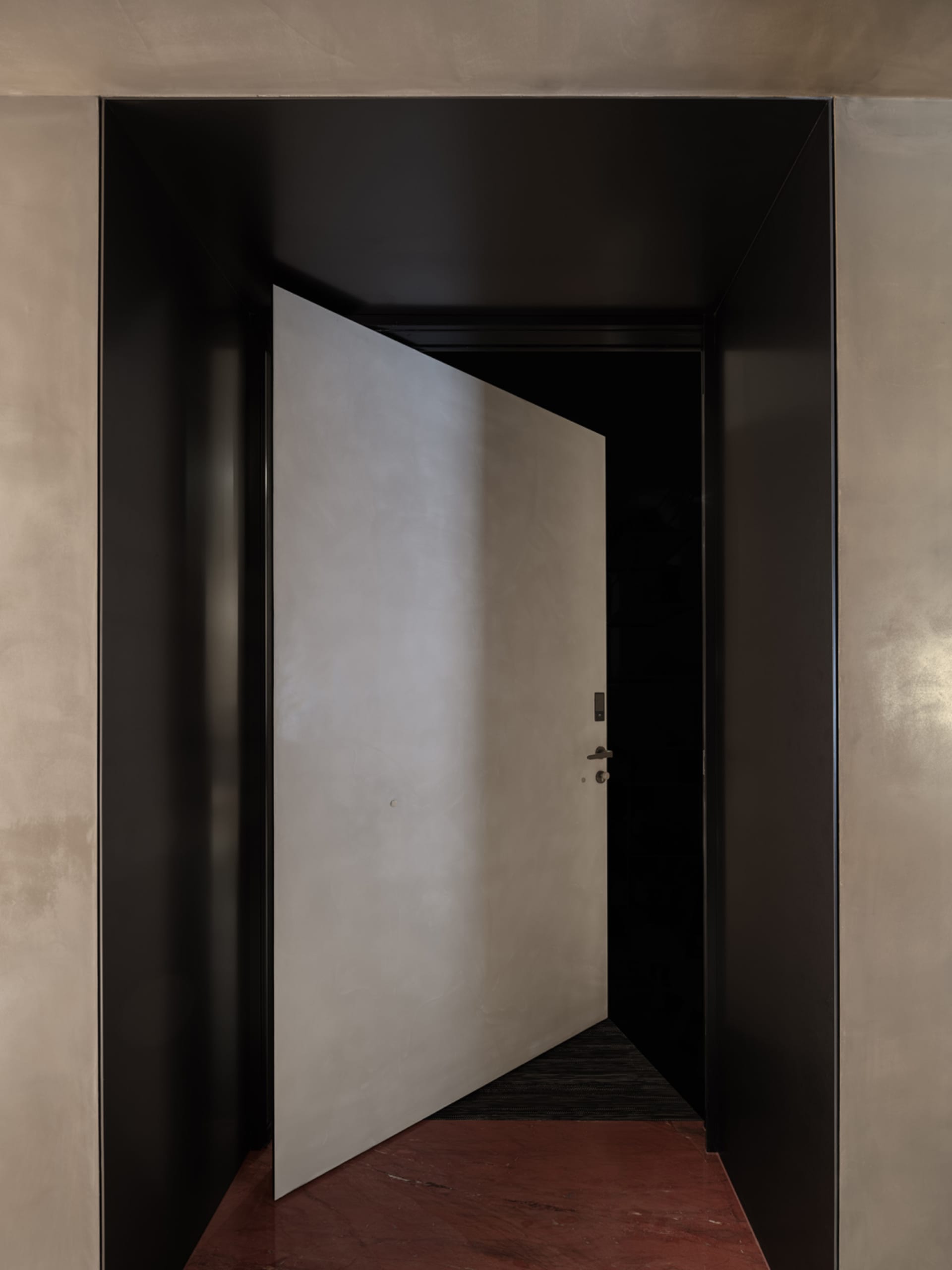 A modern entrance featuring a metallic grey panel, open to reveal an enclosed space.