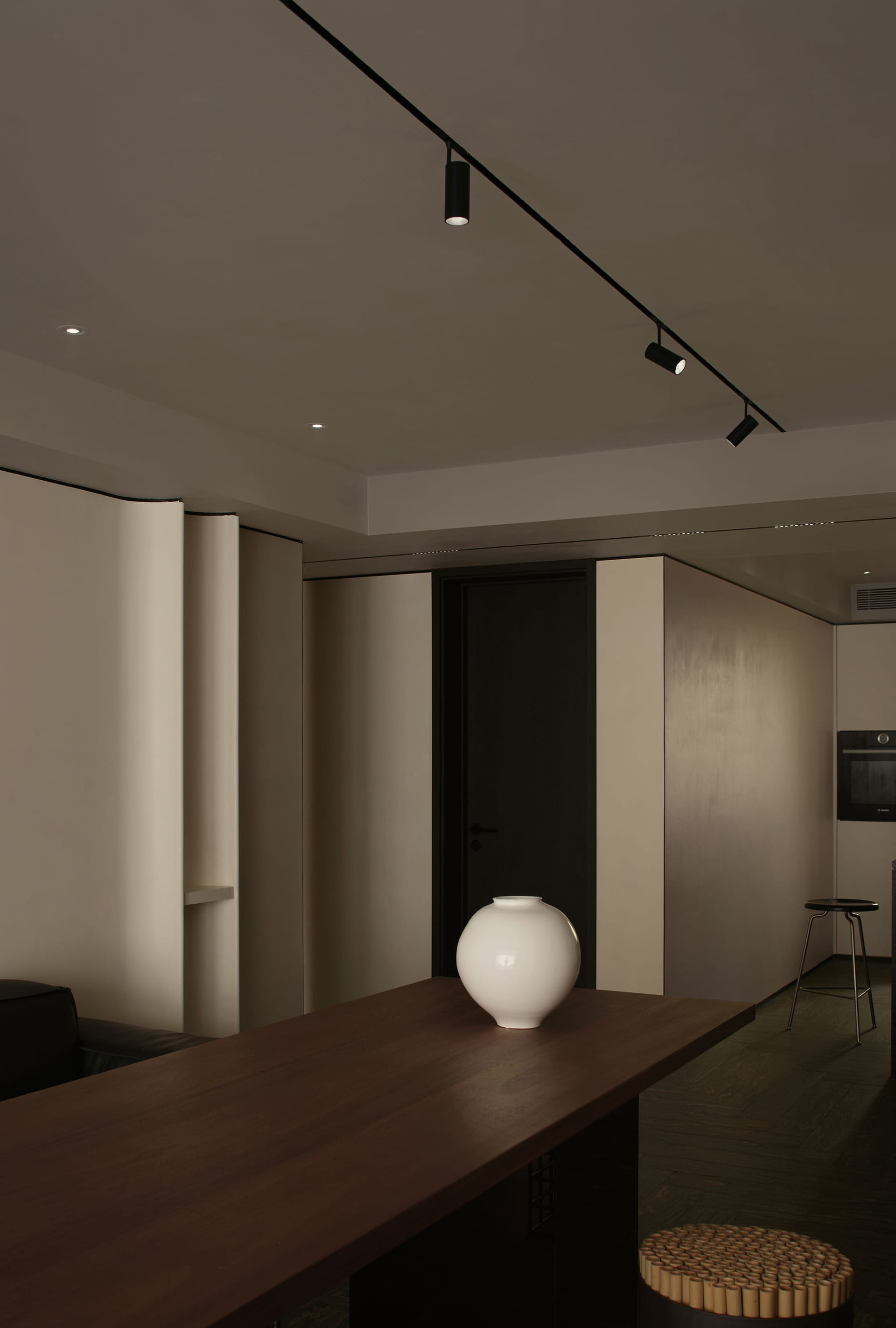 Modern minimalist dining room with a wooden table and white vase.