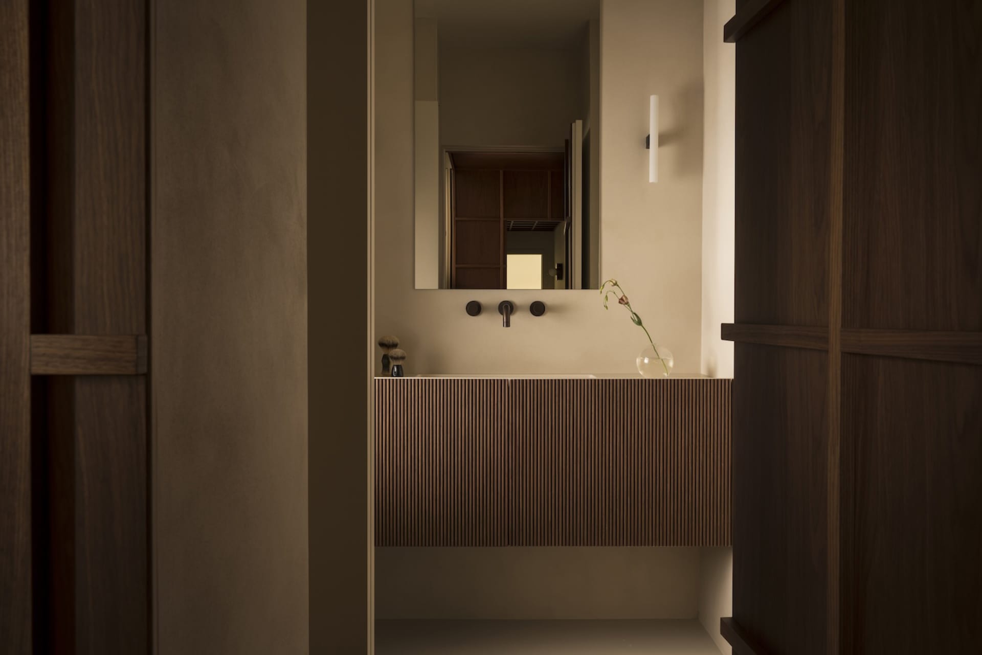 A minimalist bathroom with a wooden vanity and ceramic sink.