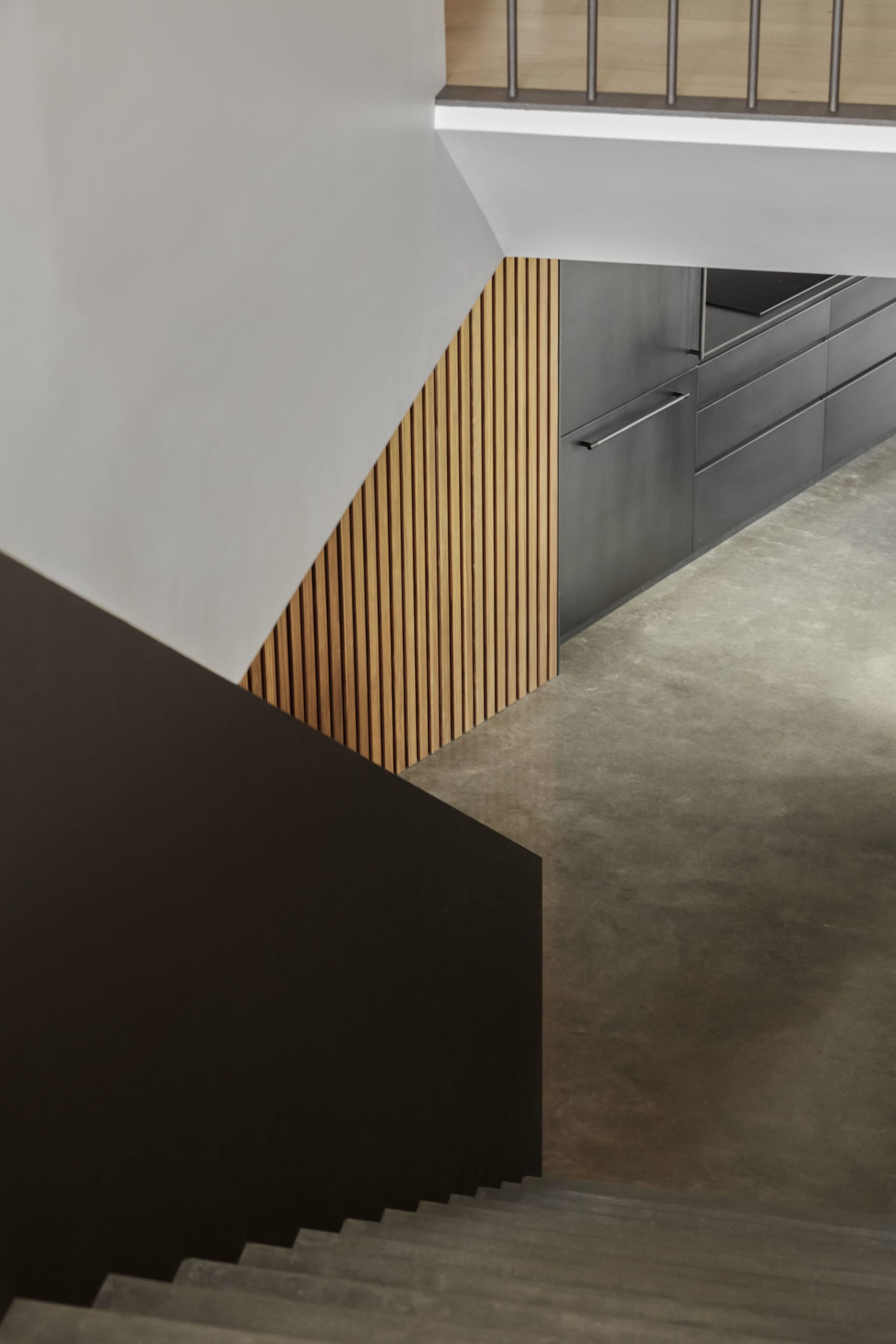 A modern kitchen with wooden paneling and dark concrete flooring.