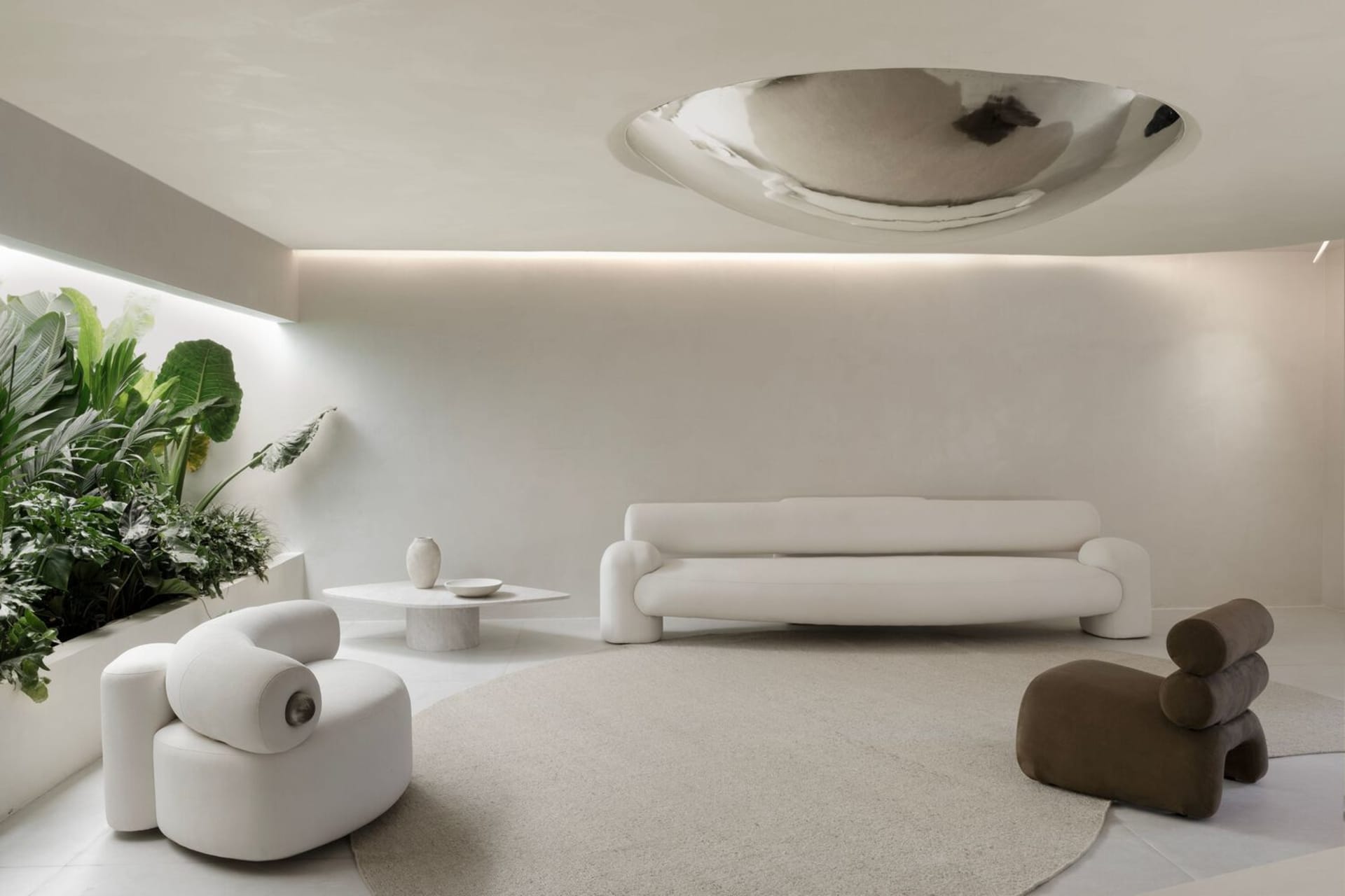 Modern minimalist living room with fabric furniture, metal accents, and green plants.