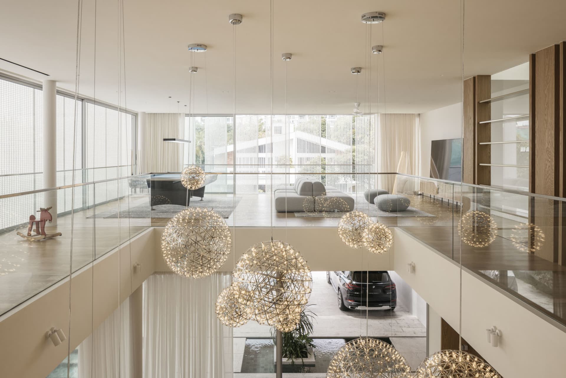 A modern living room with metallic chandeliers and glass windows.