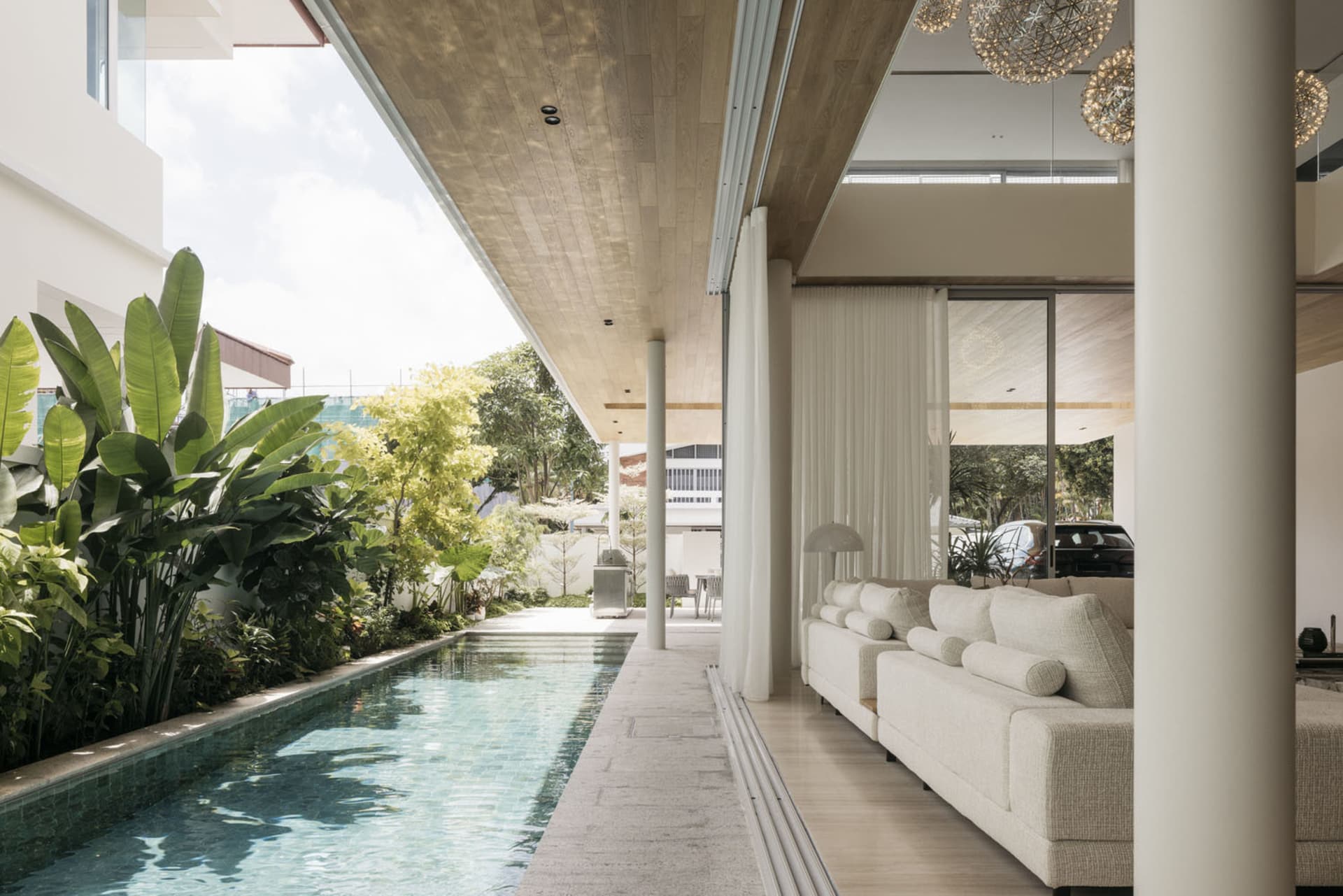 A modern living room featuring a swimming pool, marble flooring, and wooden ceiling.