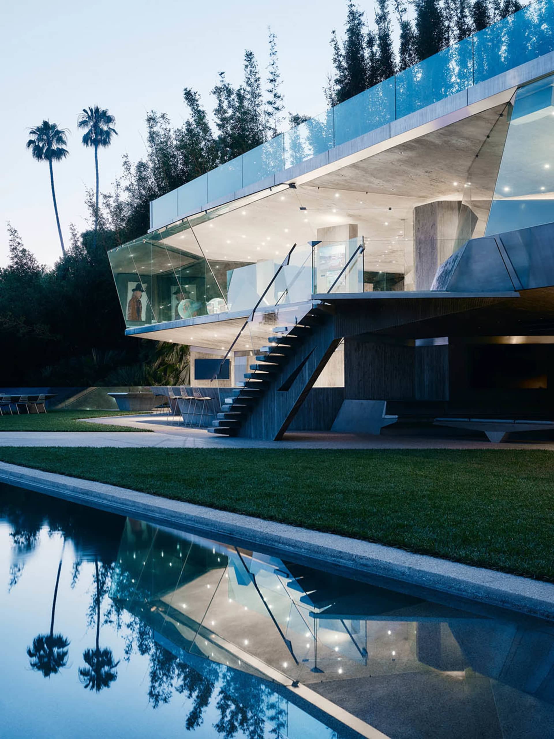 A modern residential building with glass and concrete exterior. Features include large windows, outdoor pool, and landscaping