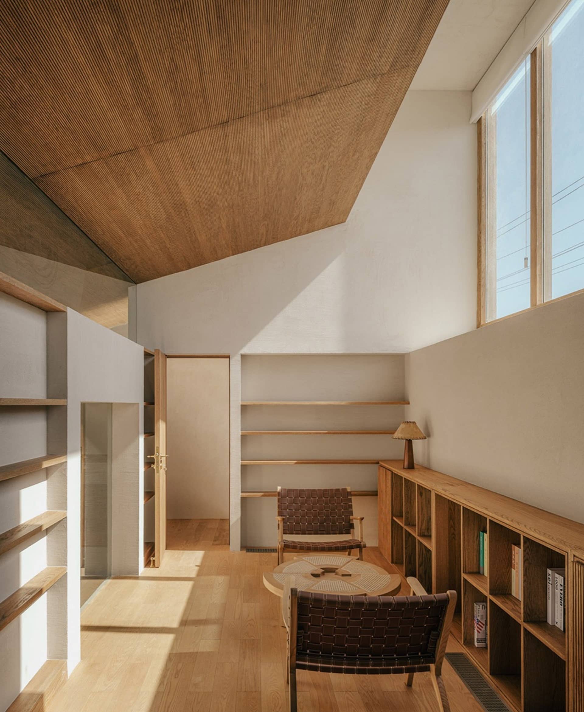 A minimalist living room with wooden furniture and shelves.