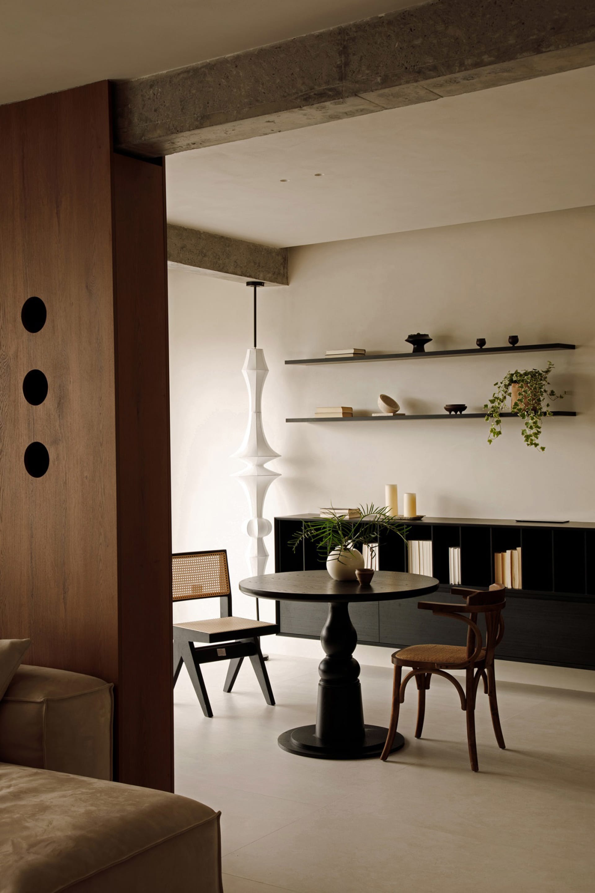A modern interior space featuring a wooden table, chairs, and bookshelf with decorative elements.